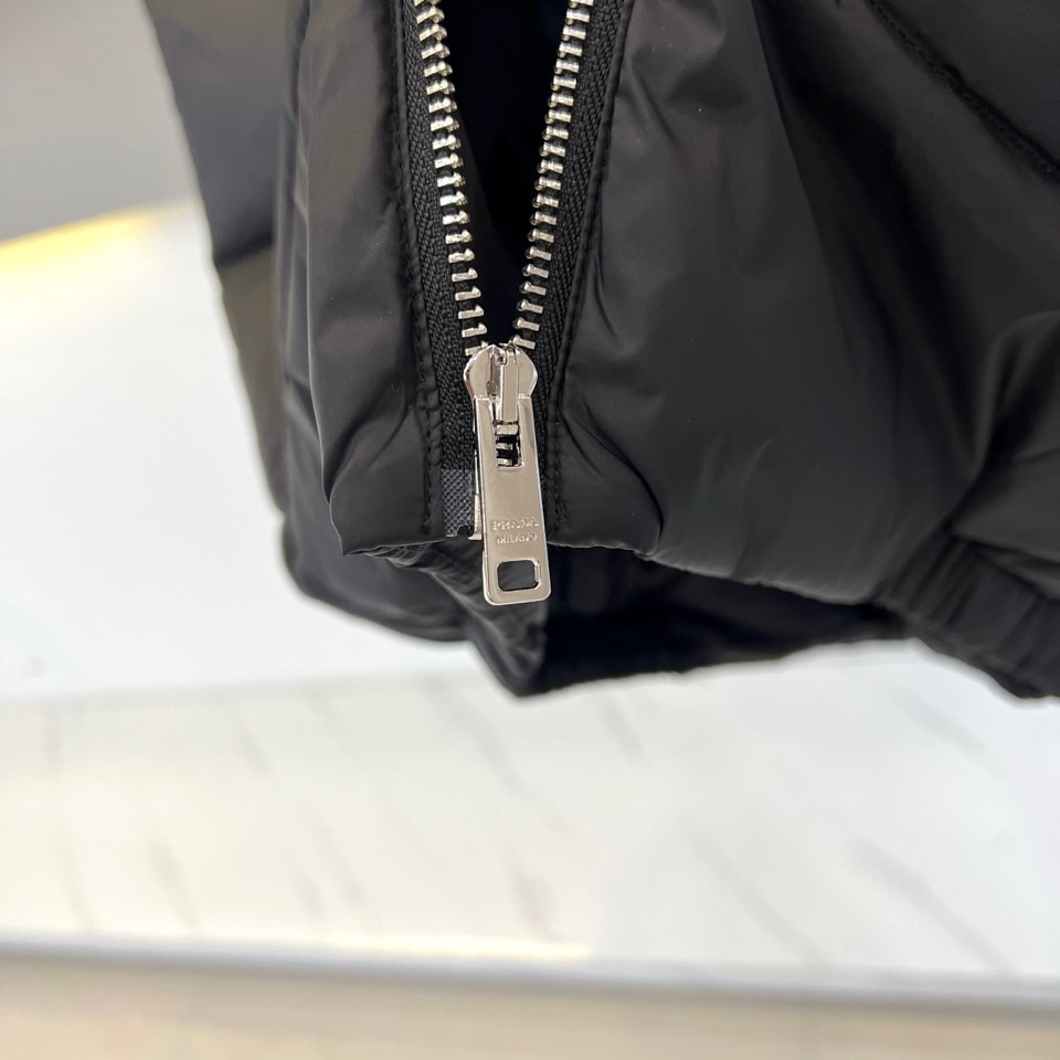 Prad普拉达、2025秋冬新品羽绒马甲以极简美学诠释实用主义时尚。这款黑色马甲采用经典无袖设计，通过精