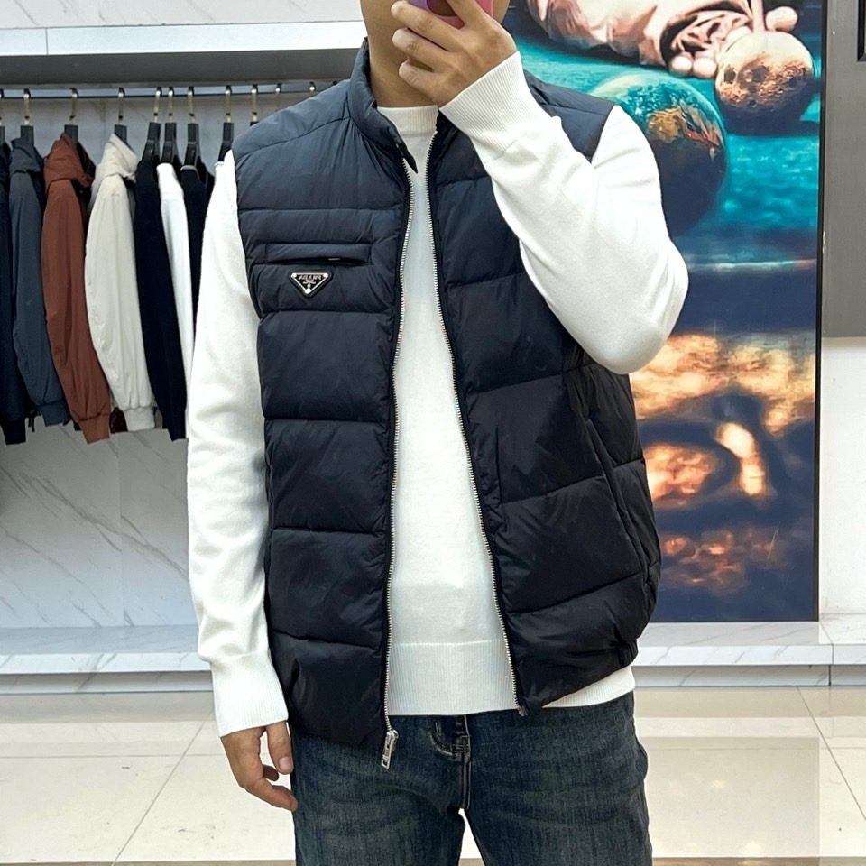 Prad普拉达、2025秋冬新品羽绒马甲以极简美学诠释实用主义时尚。这款黑色马甲采用经典无袖设计，通过精