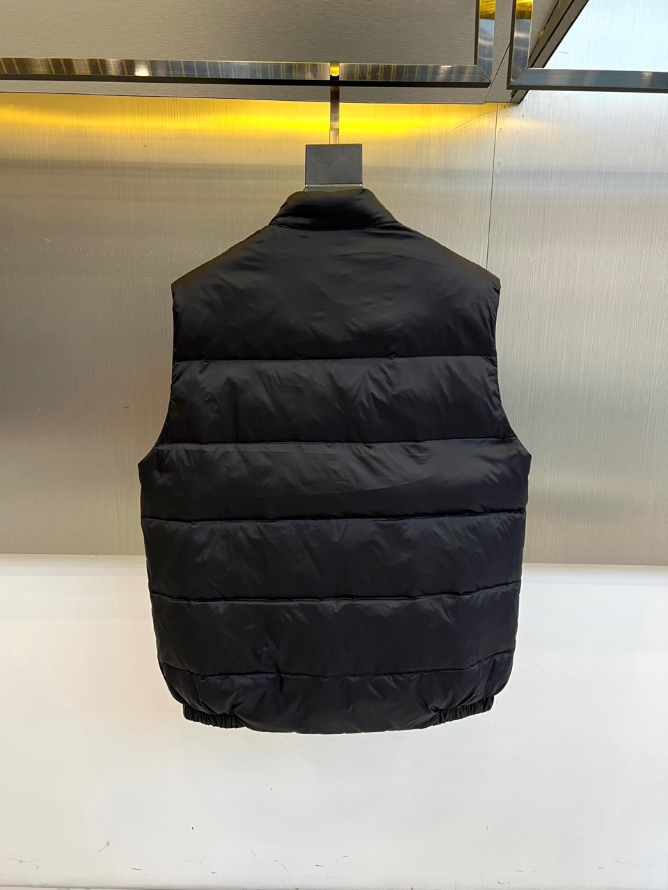 Prad普拉达、2025秋冬新品羽绒马甲以极简美学诠释实用主义时尚。这款黑色马甲采用经典无袖设计，通过精