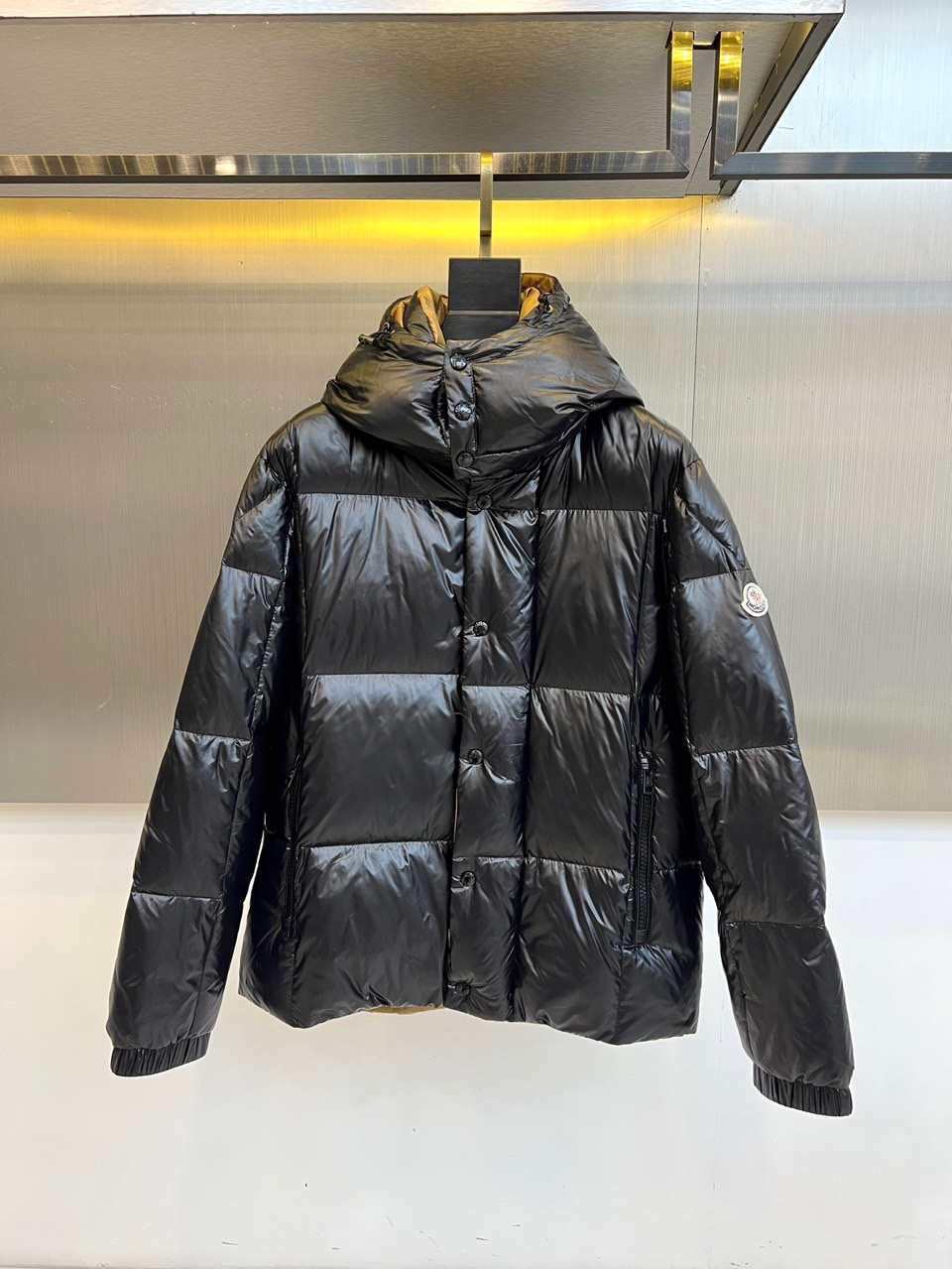 NO:685896,Mon, the 2025 autumn and winter new down jacket, has a hooded design with an adjustable black drawstring to enhance windproof practicality. The neatly arranged black buttons on the front of the body become the visual focus, serving both decorative and closing functions. The brand badge on the top of the left sleeve shows off its identity in a low-key manner, and the fluffy padding outline ensures excellent warmth.  The fabric and lining are both made of nylon, which is light, wear-resistant and has good windproof properties. The filling is a golden ratio of 90% duck down and 10% feather, which strikes a balance between fluffiness and warmth retention efficiency. The product is made in Romania with precision. The label indicates that it needs to be washed separately and gently at 30°C water temperature. Do not iron. It is recommended to turn the clothes over and remove the removable accessories before washing to maintain the best shape.  This down jacket perfectly integrates functional details and simple design. The brown color is easy to match. It can not only meet the protective needs of outdoor activities, but also can be integrated into daily urban wear, showing a low-key and professional texture style. 48-56 (model 173, 143 pounds, upper body size 50),, Moncler, down jacket, gold, hats,19860909Mon蒙口、2025秋冬新品羽绒服,连帽设计搭配可调节黑色抽绳,增强防风实用性.衣身前襟整齐排列的黑色纽扣成为视觉焦点,兼具装饰与闭合功能.左袖上方的品牌徽章低调彰显身份,蓬松的填充轮廓确保卓越保暖性. 面料与里料均采用锦纶,轻盈耐磨且具备良好的防风性能.填充物为90鸭绒与10羽毛的黄金配比,在蓬松度与保暖效率间取得平衡.产品于罗马尼亚精工制造,标签提示需30℃水温单独轻柔洗涤,不可熨烫,建议翻转衣物并取下可拆卸配件后清洗,以保持最佳形态. 这款羽绒服将功能性细节与简约设计完美融合,棕色系易于搭配,既能应对户外活动的防护需求,也可融入都市日常穿搭,展现出低调而专业的质感风格.48-56（模特173,143斤上身50码）,,Moncler,down jacket,gold,hats,,Men's clothing