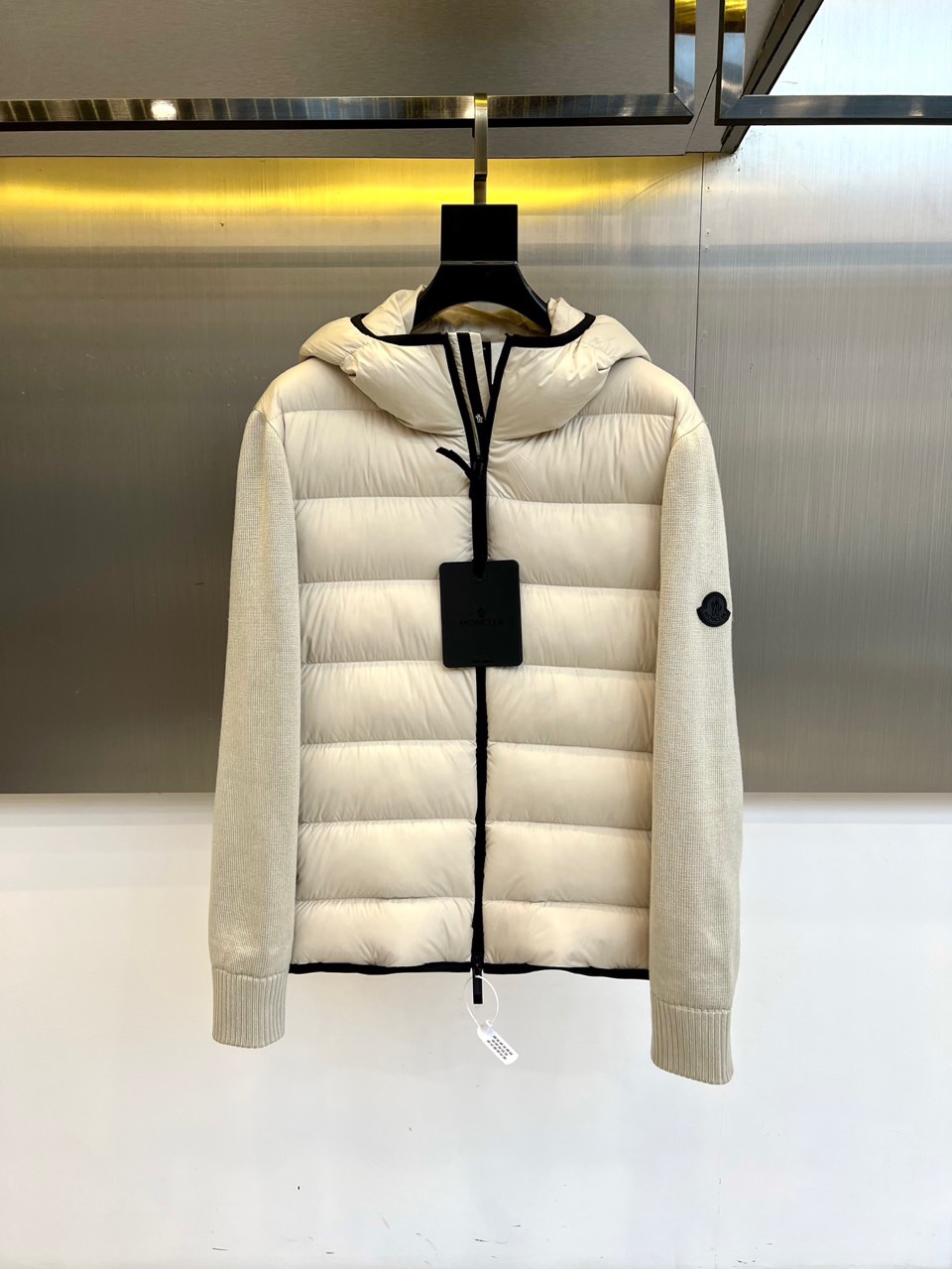 NO:684308,MON Meng Mouth (Goose Down), the new 2025 autumn and winter down jacket, interprets high-end outdoor aesthetics with a simple hooded design. It adopts a windproof zipper closure design and is equipped with an adjustable drawstring hood to enhance practical performance. The body uses diamond quilting technology to lock high-quality white goose down filling to ensure light warmth; the sleeves are spliced with elastic knitted fabric to give the arms free space. The left sleeve is embellished with the classic brand circular logo, low-key highlighting the luxury gene. The fabric is made of high-performance windproof material,  Filled with 90% white goose down and 10% feathers, it reaches a professional-grade warmth index. Its style perfectly balances functionality 19860909MON蒙口（鹅绒）、2025秋冬新品羽绒服,以简约连帽设计诠释高端户外美学.采用防风拉链开合设计,搭配可调节抽绳连帽,增强实用性能.衣身采用菱形绗缝工艺锁定优质白鹅绒填充,确保轻盈保暖性；袖部拼接弹性针织面料,赋予手臂自由活动空间.左袖点缀经典品牌圆形徽标,低调彰显奢华基因.面料选用高性能防风材质,内填充90白鹅绒与10羽毛,达到专业级保暖指数.其风格完美平衡功能性与时尚感,米白色调清新百搭,既能搭配运动裤装打造滑雪造型,亦可搭配休闲单品应对都市寒冬.这件羽绒服以蒙口标志性的工艺标准,成为冬日户外探险与都市生活的全能之选.48-56（模特173,143斤上身50码）,,Moncler,down jacket,hats,,Men's clothing