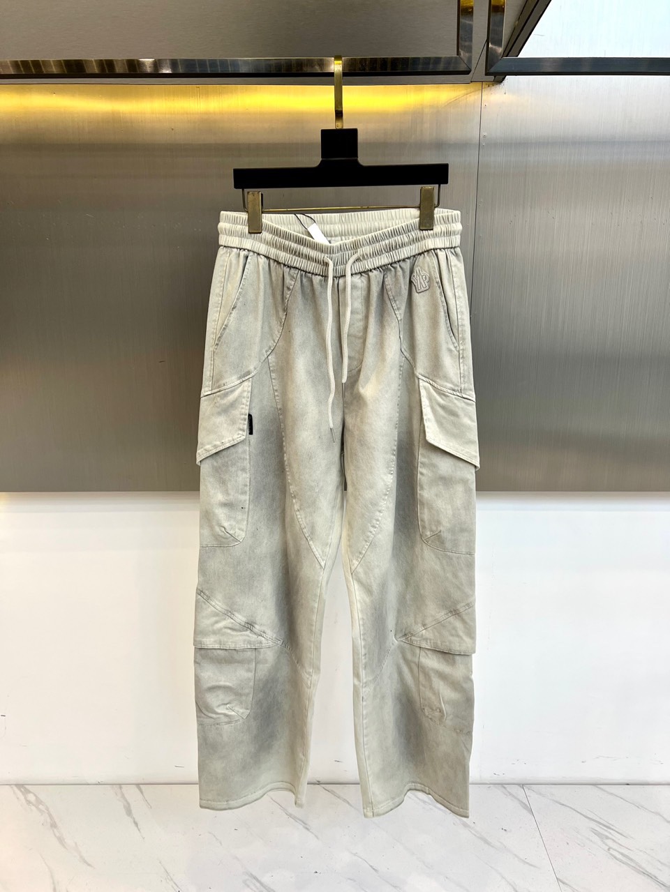 NO:684327,[Mask | Functional style overalls] Elastic waistband｜Three-dimensional pockets｜Simple embroidered logo Elastic drawstring waistband Light gray fabric with white laces, freely adjustable to fit the waistline, taking into account comfort and neatness. Multi-pocket functional design Three-dimensional divided pockets on the trousers body enhance practical storage functions, while creating a rich visual outline and interpreting urban functional aesthetics. Exquisite detail embellishments  The left leg is partially embroidered with a small logo, which is a low-key embellishment of brand recognition and injects delicate texture into the simple version. The cool gray tone fabric is made of light gray matte material, combined with neat tailoring, suitable for daily commuting and urban outdoor scenes, creating a cool and simple style. M-3XL (order information height, weight and waistline), Moncler,19860909【蒙口 | 机能风工装裤】 松紧腰头｜立体口袋｜简约刺绣标志 松紧抽绳腰头 浅灰面料搭配白色系带,自如调节贴合腰线,兼顾舒适与利落感. 多口袋机能设计 裤身立体分割口袋,强化实用收纳功能,同时塑造层次丰富的视觉轮廓,演绎都市机能美学. 精致细节点缀 左腿局部刺绣小标,低调点缀品牌辨识度,为简约版型注入细腻质感. 冷感灰调面料 选用浅灰哑光材质,配合利落剪裁,适配日常通勤与城市户外场景,打造冷感简约型格.M-3XL（下单情报身高体重腰围）,,Moncler,,Men's clothing