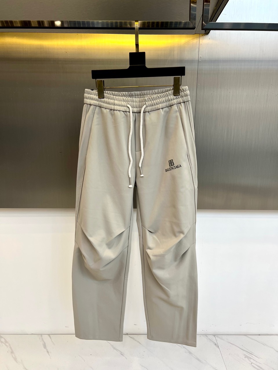 NO:684300,[BALENCIAGA｜Pleated deconstructed casual pants] Elastic drawstring waistband｜Three-dimensional pleat design｜Logo print on left leg Iconic pleat technology The trousers are integrated with three-dimensional pleats, breaking the conventional flat tailoring, forming a natural drape texture, creating a relaxed yet structured silhouette. Loose silhouette tailoring adopts an oversize loose version, combined with drape fabrics, to create a lazy and avant-garde wearing attitude while retaining freedom of movement. Logo printing on the left leg  The 'BB BALENCIAGA' brand logo is eye-catchingly printed on the outside of the left thigh. The black bold letters highlight the street genes and enhance visual recognition. Elastic drawstring waistband. The light gray elastic waistband is paired with a white webbing drawstring. The fit can be adjusted at will, taking into account comfort and simple functional style.  Suitable for pairing with silhouette tops or simple separates, highlighting the deconstructed details and brand logo of the trousers themselves, creating a daily look that combines street style with high fashion. M-3XL (please state your height, weight and waistline when placing an order),,balenciaga,versace,19860909【BALENCIAGA｜褶皱解构休闲裤】 松紧抽绳腰头｜立体褶皱设计｜左腿标志印花 标志性褶皱工艺 裤身融入立体褶皱处理,打破常规平面剪裁,形成自然垂坠的纹理感,塑造松弛而不失结构的轮廓. 宽松廓形剪裁 采用oversize宽松版型,结合垂感面料,营造慵懒前卫的穿着态度,同时保留活动自由度. 左腿标志印花 左大腿外侧醒目印有「BB BALENCIAGA」品牌标识,黑色粗体字母凸显街头基因,强化视觉辨识度. 松紧抽绳腰头 浅灰色松紧腰头搭配白色织带抽绳,可随意调节贴合度,兼顾舒适性与简约机能风格. 适合搭配廓形上衣或简约单品,突出裤装本身的解构细节与品牌标识,打造兼具街头感与高级时装的日常造型.M-3XL（下单请报身高体重腰围）,,balenciaga,versace,,Men's clothing