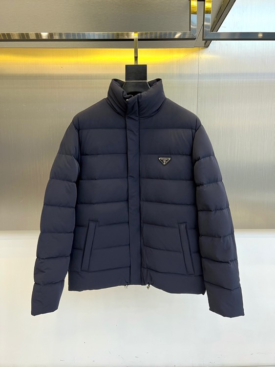 NO:684323,Prada, the new down jacket for autumn and winter 2025, adopts a neat stand-up collar design and is equipped with a smooth zipper opening and closing system. The body is outlined with a three-dimensional outline through precise diamond quilting technology, which effectively fixes the high-quality duck down filling. The brand's iconic triangular metal logo is embellished on the left chest, and the hidden pockets on both sides combine practicality and simple lines. The fabric is made of high-density windproof material, and is filled with high-quality duck down to ensure light warmth.  The style is a perfect fusion of Italian rationalism and practical philosophy. The slim tailoring maintains warmth without looking bulky. The navy blue tone shows a calm temperament, and the stand-up collar design can adjust the styling level according to needs. It can be paired with formal pants to show business casual charm, or combined with jeans to create an urban daily look. From triangular badges to precision quilting  , Every detail reflects Prada’s pursuit of functional aesthetics. This down jacket is not only a practical equipment to resist the cold winter, but also becomes a valuable investment in winter wardrobe with its low-key and luxurious texture. 48-56 (model weighs 173,143 pounds, upper body size 50),, prada, prada, jeans, down  jacket,19860909Prad普拉达、2025秋冬新品羽绒服,款式采用利落立领设计,搭配顺滑拉链开合系统,衣身通过精准的菱形绗缝工艺勾勒出立体轮廓,有效固定优质鸭绒填充物.左胸点缀品牌标志性三角形金属徽标,两侧隐形口袋兼顾实用性与简约线条.面料选用高密度防风材质,内填充优质鸭绒确保轻盈暖意. 风格上完美融合意式理性主义与实用哲学,修身剪裁既保持保暖性又不显臃肿.海军蓝色调彰显沉稳气质,立领设计可随需求调整造型层次.既能搭配正装裤展现商务休闲魅力,亦可结合牛仔裤打造都市日常造型.从三角形徽章到精准绗缝,每处细节都体现普拉达对功能美学的追求,这件羽绒服不仅是抵御寒冬的实用装备,更以低调奢华的质感成为冬日衣橱的价值投资.48-56（模特173,143斤上身50码）,,prada,prada,jeans,down jacket,,Men's clothing