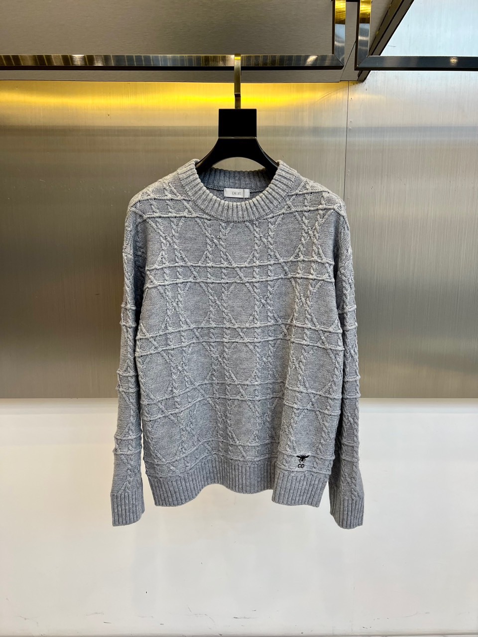 NO:684304,Dio, the new women's sweater for autumn and winter 2025, uses high-end gray tones to interpret the perfect fusion of French elegance and modern art. This round-neck sweater uses exquisite three-dimensional jacquard technology, and the body is covered with geometric textures and the brand's classic houndstooth pattern. The alternating use of different stitches creates a layered relief texture. The left cuff is embellished with the iconic bee embroidery, decorated with gold  Silk threads outline smart details, highlighting Dior's profound craftsmanship heritage. Cotton yarns are treated with special spindles, which are both soft and skin-friendly and have good shape retention. The slim-fitting but not close-fitting tailoring takes into account comfort and curves. Whether it is paired with a leather skirt to show a modern temperament, or combined with wide-leg pants to create a casual and elegant style, it can become a link between day and night in the autumn and winter wardrobe.  Versatile single product, interpreting Dior's fashion philosophy of integrating the spirit of haute couture into daily wear. 48-56 (model weighs 173,143 pounds, upper body size 50),, dior, dior, versace, skirts, sweaters,19860909Dio迪奥、2025秋冬新品女士毛衣,以高级灰色调演绎法式优雅与现代艺术的完美融合.这款圆领毛衣采用精湛的立体提花工艺,衣身布满几何纹理与品牌经典千鸟格纹样,通过不同针法的交替运用形成富有层次的浮雕质感.左袖口点缀标志性蜜蜂刺绣,以金色丝线勾勒出灵动细节,彰显迪奥深厚的工艺传承.棉质纱线经过特殊纺锤处理,兼具柔软亲肤性与良好保形性.修身而不贴身的剪裁兼顾舒适度与曲线美,无论是搭配皮革半裙展现摩登气质,还是与阔腿裤组合营造休闲优雅风范,都能成为秋冬衣橱中连接日与夜场合的 versatile 单品,诠释迪奥将高级定制精神融入日常穿着的时尚哲学.48-56（模特173,143斤上身50码）,,dior,dior,versace,skirts,sweaters,,Men's clothing