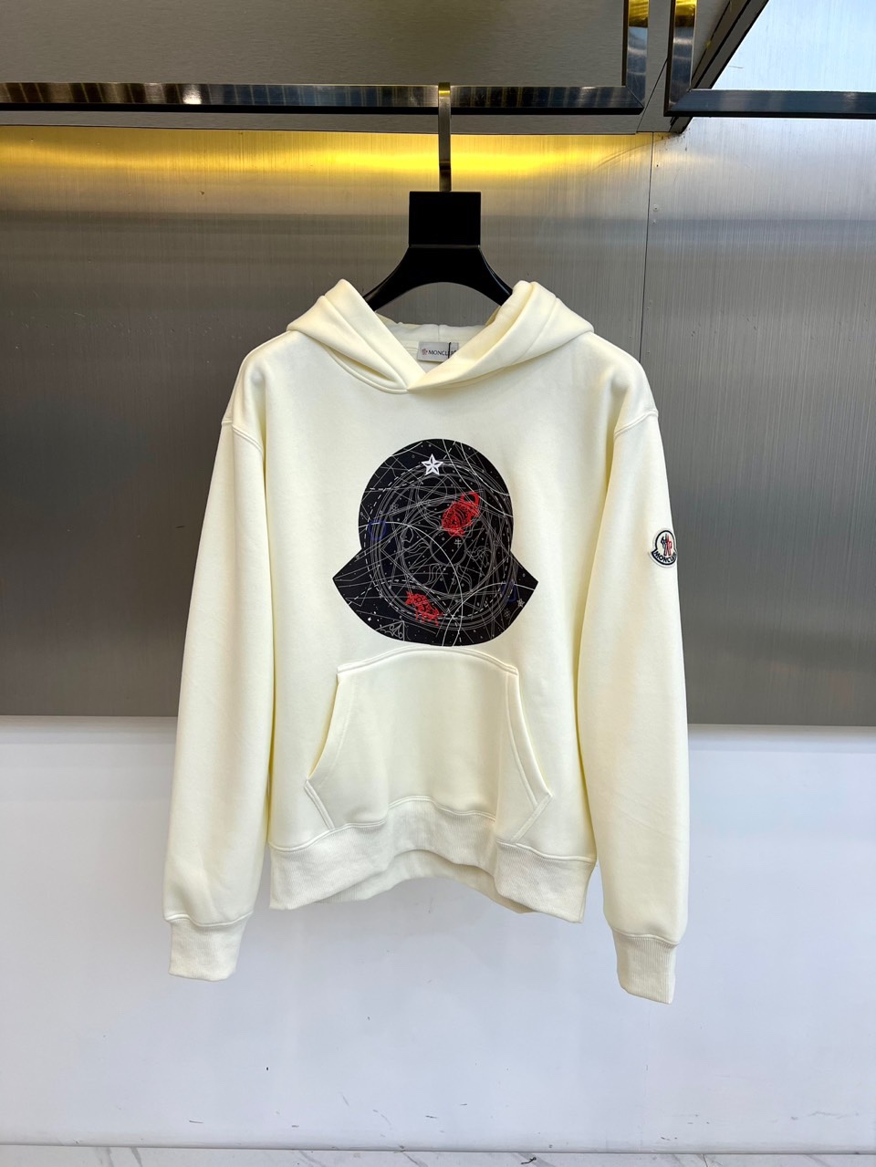 NO:684309,Meng Mouth, 2025 autumn and winter, launches a new hooded sweatshirt, based on pure white, with a simple silhouette infused with a sense of street art. The eye-catching black circular pattern is designed on the chest, incorporating interlaced lines, red embellishments and star elements to create a trend symbol with visual tension. The loose hood design and classic logo embroidery on the cuffs take into account casual comfort and detailed texture. Practical pockets are added on both sides of the hem.  Improve functionality and styling level. The whole is based on street style, cleverly integrating sports genes and fashion expression, adapting to daily wear and personality style, becoming a dynamic item in the autumn and winter wardrobe that is both recognizable and practical. S-4XL (model 173-140 pounds upper body size M), Moncler, hoodie, sweatshirts, hats,19860909蒙口、2025秋冬,推出全新连帽卫衣,以纯白为基调,简约廓形中注入街头艺术感.胸前设计醒目的黑色圆形图案,融入线条交织、红色点缀与星星元素,打造富有视觉张力的潮流符号.宽松连帽设计与袖口经典logo刺绣,兼顾休闲舒适与细节质感.下摆两侧加入实用口袋,提升功能性与造型层次.整体以街头风格为内核,将运动基因与时尚表达巧妙融合,适配日常穿搭与个性造型,成为秋冬衣橱中兼具辨识度与实穿性的活力单品.S-4XL（模特173-140斤上身M码）,,Moncler,hoodie,sweatshirts,hats,,Men's clothing