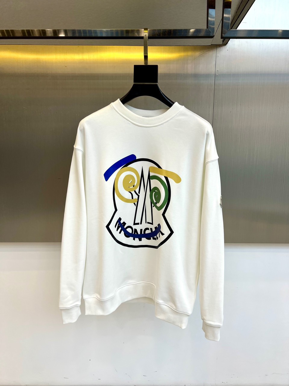 NO:684312,For the autumn and winter of 2025, Moncler launches a new white round-neck sweatshirt, which presents a casual and simple style with a loose, dropped-shoulder silhouette. The front of the sweatshirt is decorated with an artistic abstract pattern, and black lines outline a tense image outline, and are cleverly integrated into blue, yellow, green and other colors, with the word 'MONCLER' interspersed throughout, to highlight individuality without losing recognition. Soft  The soft and comfortable fabric combines warmth retention with daily practicality. Whether paired with jeans or sweatpants, you can easily create an autumn and winter look that combines street fashion and artistic temperament, injecting vitality and fashionable ideas into daily wear. S-3XL (model 198609092025秋冬Moncler推出新款白色圆领卫衣,以宽松的落肩廓形呈现随性简约风格.卫衣正面饰有极具艺术感的抽象图案,黑色线条勾勒出充满张力的形象轮廓,并巧妙融入蓝、黄、绿等色彩,其间穿插“MONCLER”字样,彰显个性又不失辨识度.柔软舒适的面料兼顾保暖性与日常实穿性,无论是搭配牛仔裤或运动裤,皆可轻松打造兼具街头潮流感与艺术气质的秋冬造型,为日常穿搭注入活力与时尚巧思.S-3XL（模特173-140斤上身M码）,,hoodie,sweatshirts,jeans,,Men's clothing