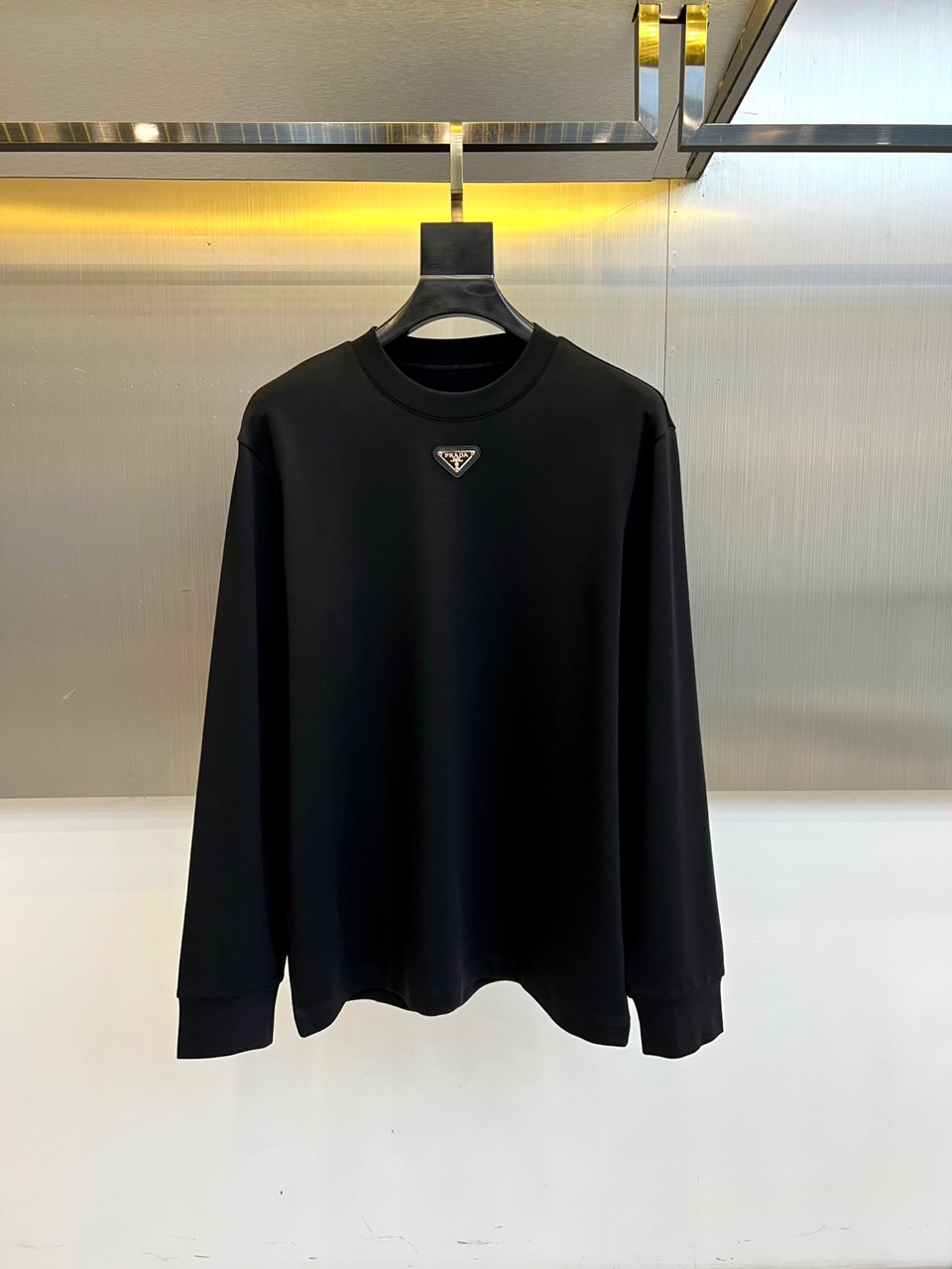 NO:684314,Prada, the new men's modal sweatshirt for autumn and winter 2025, uses classic black to interpret low-key and luxurious daily aesthetics. This sweatshirt is made of 47 modal, 47 cotton and 6 spandex fabrics in a golden ratio, which not only retains the skin-friendly breathability of cotton, but also is endowed with modal ingredients.  It is as soft and drapey as velvet, while spandex provides just the right amount of elasticity and flexibility. The iconic round neck design is paired with a loose fit, creating a relaxed and relaxed silhouette. The brand's iconic triangular metal logo is embellished on the chest, with the word 'PRADA' engraved on it, becoming the highlight of the overall design.  The visual focus. The ribbed cuffs and hem ensure a crisp and neat silhouette, and the side pockets are designed with practical functions in mind. The overall design injects Prada’s Italian craftsmanship genes into a sports and leisure style. It can be worn alone with casual trousers to show a simple style, or it can be worn as an inner layer with a down jacket or coat.  Create an autumn and winter look that combines comfort and luxury, perfectly interpreting the fashion attitude of modern urban men. 48-56 (model weighs 173,143 pounds, upper body size 50),, prada, prada, hoodie, sweatshirts, down  jacket,gold,19860909Prad普拉达、2025秋冬新品男士莫代尔卫衣,以经典黑色演绎低调奢华的日常美学.这款卫衣采用47莫代尔、47棉与6氨纶的黄金比例面料,既保留了棉质的亲肤透气性,又通过莫代尔成分赋予丝绒般柔软垂坠感,氨纶则提供恰到好处的弹性灵活度.标志性的圆领设计搭配宽松版型,营造出松弛有度的轮廓线条.胸前点缀品牌标志性三角形金属徽标,其上镌刻'PRADA'字样,成为整体设计的视觉焦点.罗纹袖口与下摆确保版型挺括利落,侧边插袋设计兼顾实用功能.整体设计将普拉达的意式工艺基因注入运动休闲风格,既可单独搭配休闲长裤展现简约风尚,也可作为内搭与羽绒服或大衣叠穿,打造兼具舒适度与高级感的秋冬造型,完美诠释现代都市男士的时尚态度.48-56（模特173,143斤上身50码）,,prada,prada,hoodie,sweatshirts,down jacket,gold,,Men's clothing