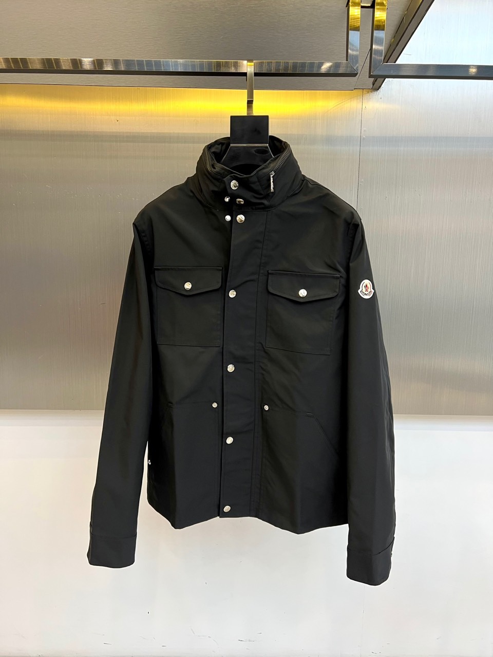 NO:726375,After the year, Mon is covered, and the new product for autumn and winter is the MON workwear-style stand-up collar jacket. Inspired by workwear aesthetics, this jacket adopts three-dimensional tailoring and multi-pocket design, which perfectly integrates practical functions and modern fashion. The stand-up collar structure is equipped with a smooth zipper opening and closing system, and there are multiple three-dimensional patch pockets on the chest and sides to enhance the storage function while maintaining smooth lines. The left sleeve is decorated with the brand's iconic embroidered badge, highlighting the luxury outdoor gene.  The fabric is made of high-tech blended materials, and the surface has been specially treated to present a fine texture, with windproof and anti-wrinkle properties. The lining is made of skin-friendly material to ensure wearing comfort, and the ribbing process enhances warmth. The beige tone is gentle and versatile, and can be paired with casual pants to create an urban outdoor style.  The overalls enhance the functional styling. Through the balance of workwear elements and luxurious details, MONCLER interprets MONCLER's design philosophy of integrating the spirit of mountain adventure into urban daily life. 48-56 (model weighs 173,143 pounds, upper body size 50),,Moncler,jackets  & coats,19860909年后 Mon蒙口、秋冬新品 MON工装风立领夹克.这款夹克以工装美学为灵感,采用立体剪裁与多口袋设计,将实用功能与现代时尚完美融合.立领结构搭配顺滑拉链开合系统,胸前及侧身设有多个立体贴袋,增强储物功能的同时保持线条流畅感.左袖饰有品牌标志性刺绣徽章,彰显奢华户外基因. 面料选用高科技混纺材质,表面经过特殊处理呈现细腻肌理,具备防风抗皱特性.内衬采用亲肤材质确保穿着舒适度,罗纹收边工艺增强保暖性.米色基调温和百搭,既可搭配休闲裤打造都市户外风格,也能配合工装裤强化机能造型.通过工装元素与奢华细节的平衡,诠释MONCLER将高山探险精神融入都市日常的设计哲学.48-56（模特173,143斤上身50码）,,Moncler,jackets & coats,,Men's clothing