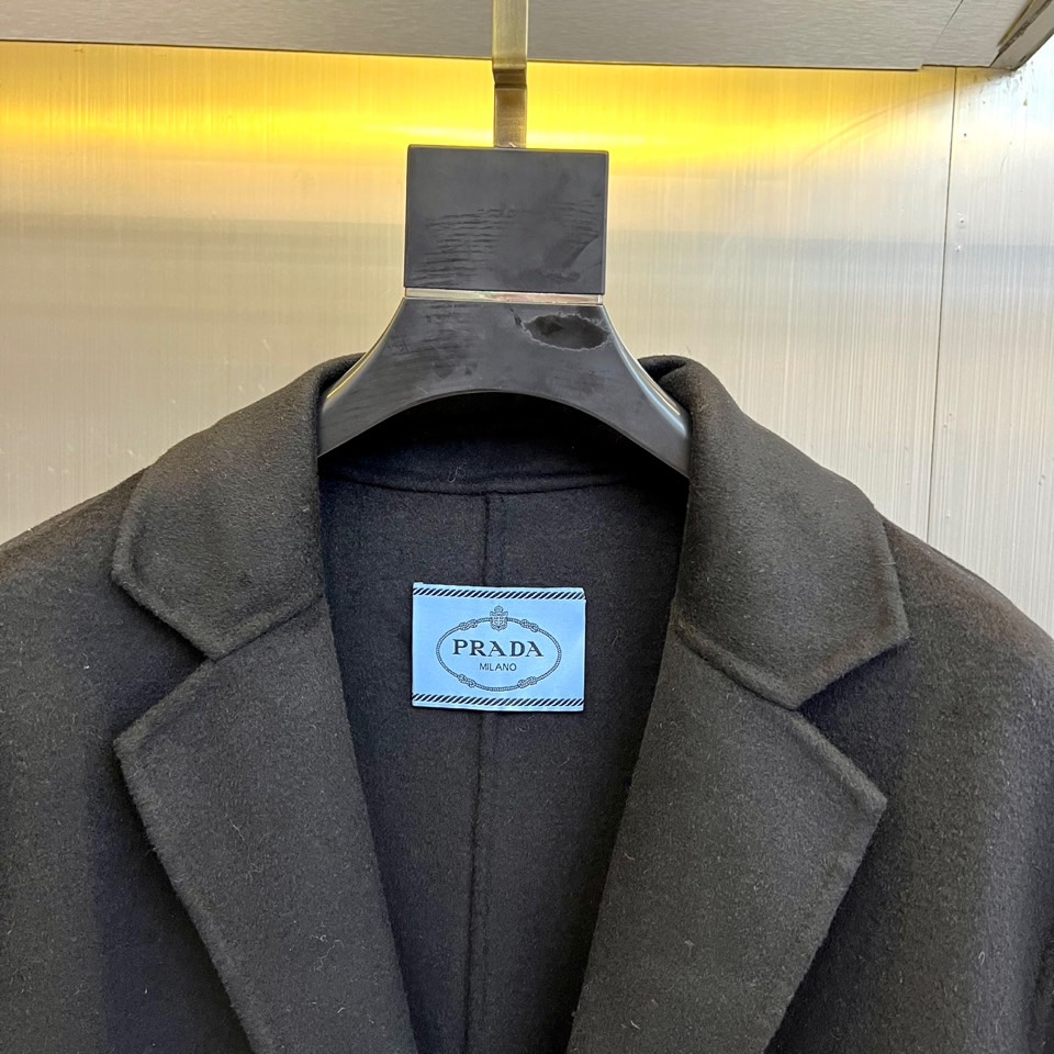 Prad普拉达、2025秋冬新品男士大衣，以经典黑色演绎永恒奢华的现代美学。这款大衣采用90%羊毛与10