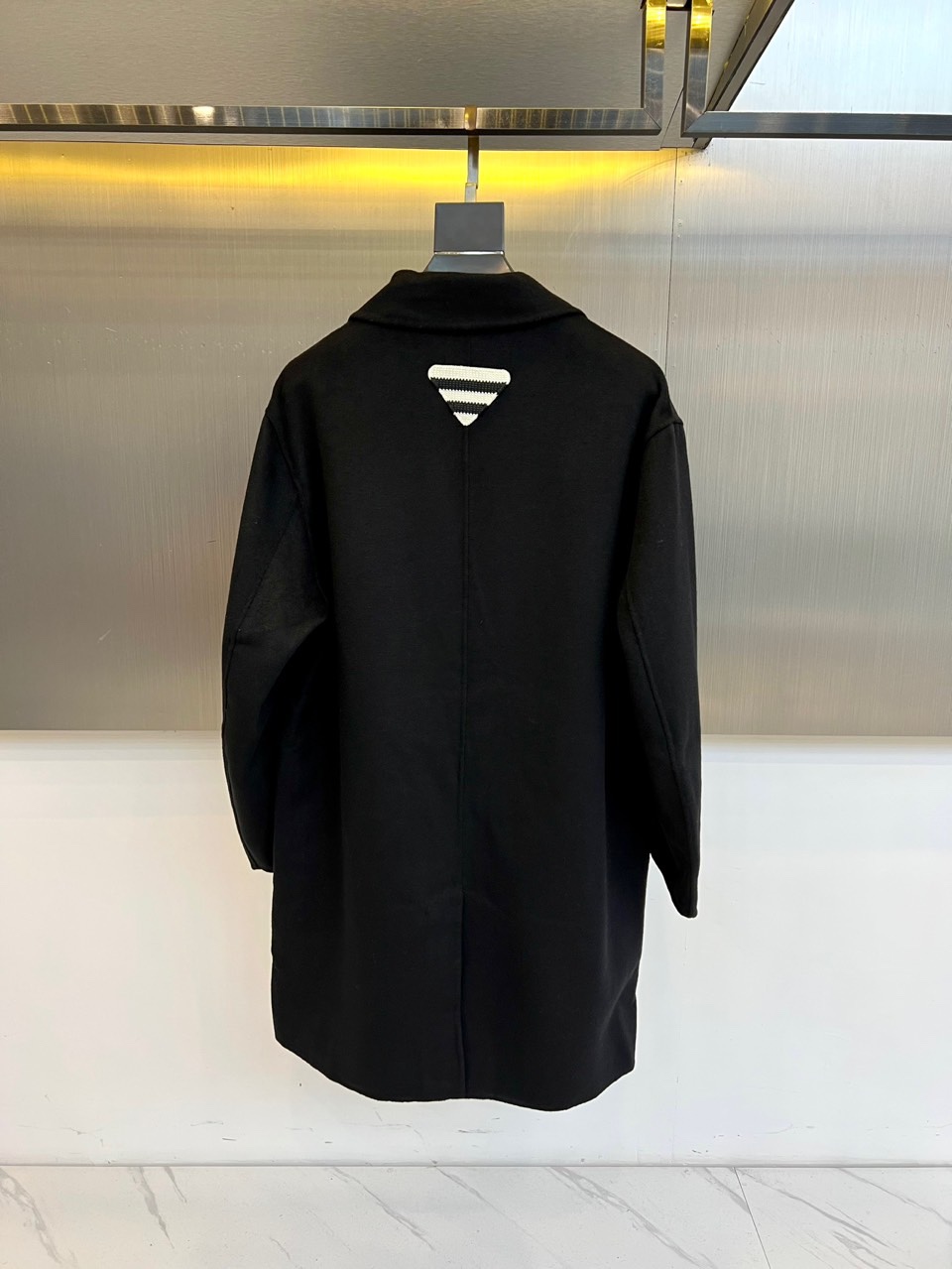 Prad普拉达、2025秋冬新品男士大衣，以经典黑色演绎永恒奢华的现代美学。这款大衣采用90%羊毛与10