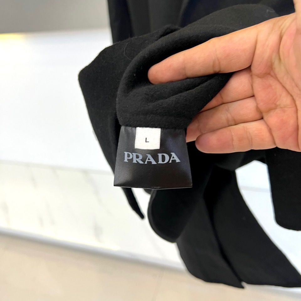 Prad普拉达、2025秋冬新品男士大衣，以经典黑色演绎永恒奢华的现代美学。这款大衣采用90%羊毛与10