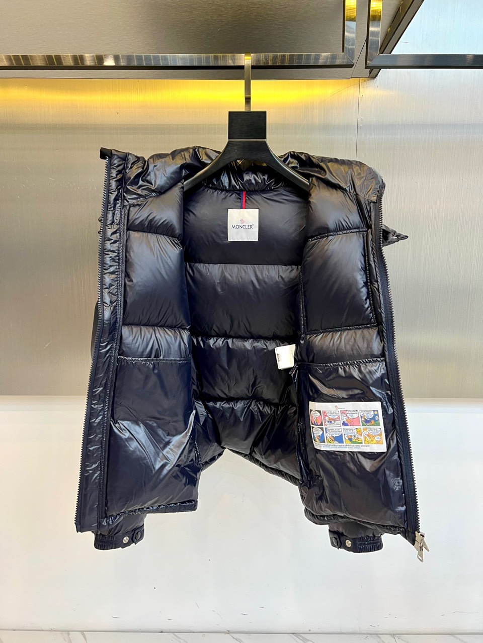 Mon蒙口（鹅绒）、2025秋冬新品羽绒服，以深蓝色亮面短款设计诠释现代都市机能美学。款式采用利落箱型剪