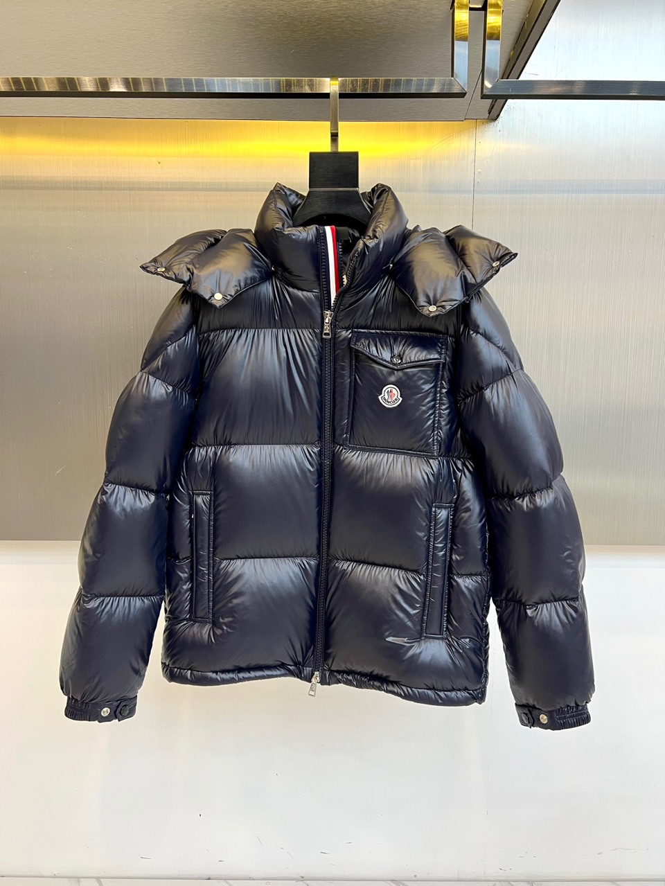 Mon蒙口（鹅绒）、2025秋冬新品羽绒服，以深蓝色亮面短款设计诠释现代都市机能美学。款式采用利落箱型剪