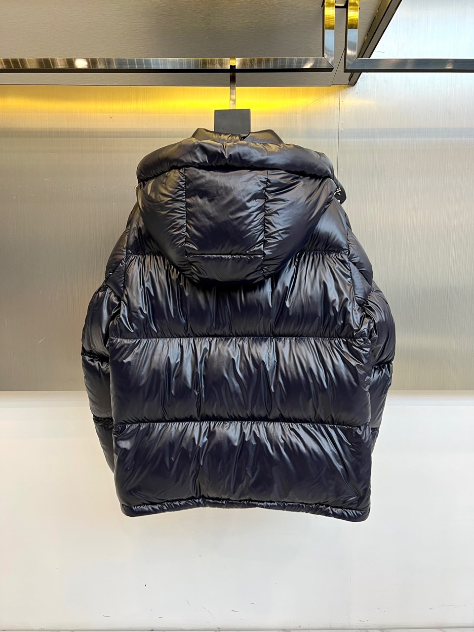 Mon蒙口（鹅绒）、2025秋冬新品羽绒服，以深蓝色亮面短款设计诠释现代都市机能美学。款式采用利落箱型剪