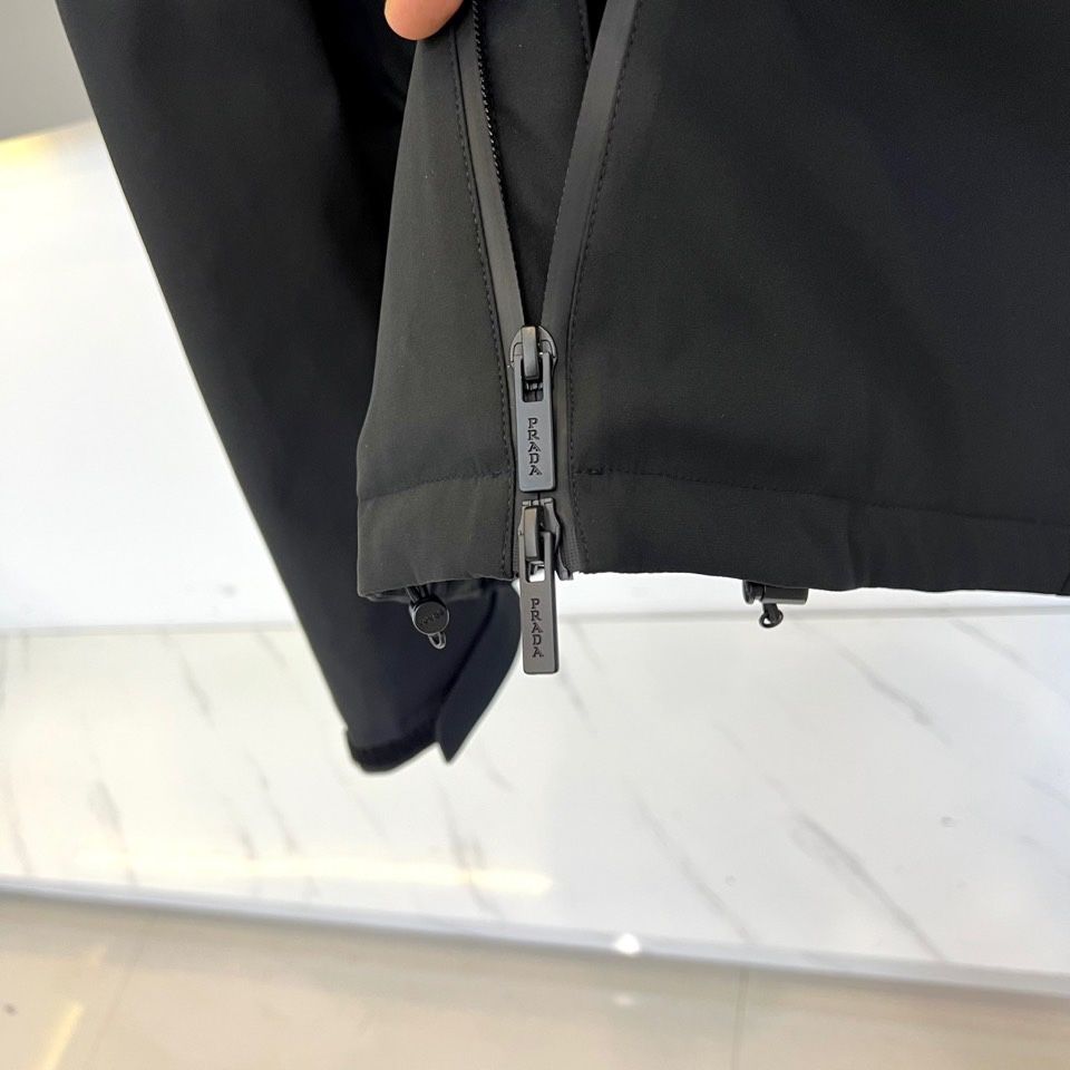 Prad普拉达（白鹅绒）、2025秋冬新品羽绒服，连帽设计搭配利落的直线条轮廓，通过精准的绗缝工艺勾勒出