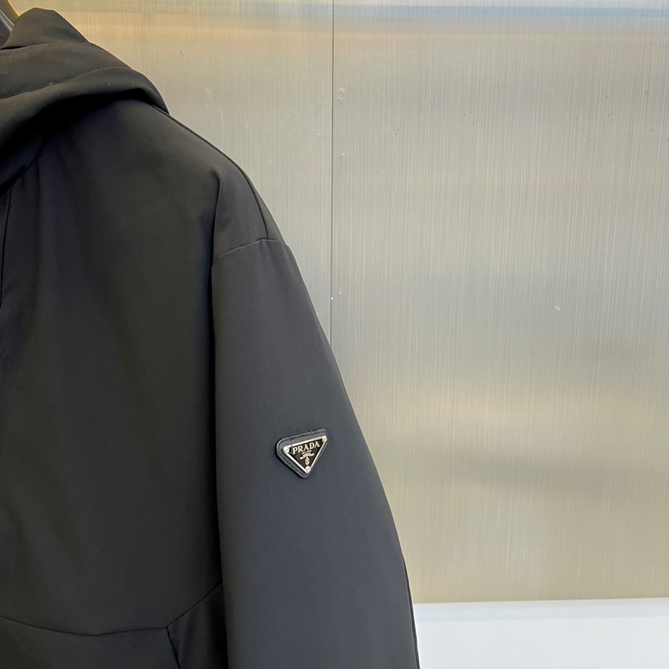 Prad普拉达（白鹅绒）、2025秋冬新品羽绒服，连帽设计搭配利落的直线条轮廓，通过精准的绗缝工艺勾勒出