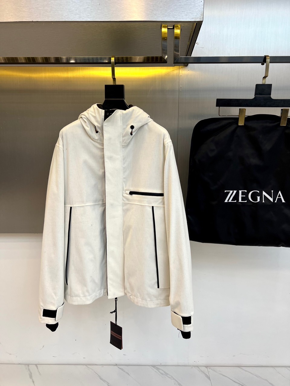 NO:703216,Zegna Zegna's new autumn and winter three-in-one down jacket interprets the concept of multi-functional wearing with minimalist aesthetics. This down jacket is available in pure white and black and gray color combinations. It adopts a detachable liner design, the outer layer is nylon windproof fabric, and the liner is filled with 90% high-quality down (of which the velvet content reaches 10%), and is combined with 9%  The elastic composite fiber layer of 1 nylon and 9 spandex forms a triple thermal insulation system. The hooded design is equipped with an adjustable drawstring, the front placket is closed with a smooth zipper, the chest is equipped with a waterproof zipper pocket, and the diagonal pockets on both sides are lined with polyester fiber. The black ribbed splicing at the cuffs contrasts sharply with the body, showing exquisite details.  Its design perfectly combines outdoor functionality with Italian elegance, ensuring freedom of movement through three-dimensional tailoring. The detachable lining can be worn alone or combined to cope with different temperatures. The white version shows a fresh and modern feel, while the black and gray color-blocking version presents a geometric beauty through taped quilting technology. From urban commuting to suburban activities, this down jacket can be adapted to different scenes in a variety of wearing modes, maintaining a light body feel while providing professional-level warmth.  The details show the craftsmanship and precise quilting to ensure even distribution of down, the adjustable brim enhances windproof performance, and the inner label clearly indicates the quality commitment of Italian design and Made in China. Whether it is paired with business casual wear or sportswear, it can show a calm and moderate fashion attitude, becoming a smart choice for the autumn and winter wardrobe of modern gentlemen who pursue quality life. S-XXL (model 173, 143 pounds, upper body size M),, zegna, down jacket, hats,19860909Zegna杰尼亚、秋冬新品三合一羽绒服以极简美学诠释多功能穿着理念.这款羽绒服提供纯白与黑灰拼色两种选择,采用可拆卸内胆设计,外层为锦纶防风面料,内胆填充90优质羽绒（其中绒子含量达10）,并结合91锦纶与9氨纶的弹性复合纤维层,形成三重保暖系统.连帽设计配备可调节抽绳,前襟采用顺滑拉链闭合,胸口设防水拉链口袋,两侧斜插口袋内衬采用聚酯纤维.袖口处的黑色罗纹拼接与衣身形成鲜明对比,展现精致细节. 其设计将户外功能性与意式优雅完美融合,通过立体剪裁确保活动自由度,可拆卸内胆既可单独穿着,又能组合应对不同气温.白色款展现清新现代感,黑灰拼色款则通过压胶绗缝工艺呈现几何美感.从都市通勤到郊外活动,这款羽绒服能以多种穿着模式适应不同场景,既保持轻盈体感又提供专业级保暖. 细节处彰显匠心工艺精准的绗缝走线确保羽绒分布均匀,可调节帽檐增强防风性能,内里标签明确标注意大利设计与中国制造的品质承诺.无论是搭配商务休闲装还是运动服饰,都能展现从容有度的时尚态度,成为追求品质生活的现代绅士秋冬衣橱中的智慧之选.S-XXL（模特173,143斤上身M码）,,zegna,down jacket,hats,,Men's clothing