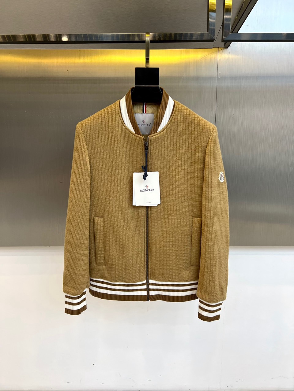 NO:712020,Mon, the new CHAFFEY series down jacket for autumn and winter 2025, interprets urban sports aesthetics in khaki tones. This down jacket adopts a classic baseball collar design, and the collar, cuffs and hem are decorated with white rib knitted edges, forming a sharp contrast in sports style. The front is equipped with a smooth zipper opening and closing system, and practical pockets on both sides take into account functionality and smooth lines. The sleeves are embellished with the brand's iconic embroidered badges, and the black and white striped details at the hem inject a lively atmosphere into the overall design.  The fabric is made of high-quality windproof material, and is filled with high-quality down to ensure lightness and warmth. Its design perfectly integrates sports elements with daily practicality. The khaki color is suitable for a variety of wearing scenarios, and the baseball collar design highlights the casual temperament. Whether it is paired with jeans to create an urban look, or paired with casual pants to show a sports style, it can easily handle different occasions.  From daily outings to weekend gatherings, this down jacket, with its iconic craftsmanship details and practical design, has become an ideal choice for both fashion and functionality in autumn and winter. The ribbed edges and striped details show the brand's pursuit of exquisite craftsmanship, making the warm item a fashionable tool to enhance the overall look. 48-56 (model 173, 143 pounds, upper body size 50),, Moncler, jeans, down jacket,19860909Mon蒙口、2025秋冬新品CHAFFEY系列羽绒服,以卡其色调演绎都市运动美学.这款羽绒服采用经典棒球领设计,领口、袖口及下摆处饰以白色罗纹针织包边,形成鲜明的运动风格对比.前襟配备顺滑拉链开合系统,两侧实用插袋兼顾功能性与流畅线条.衣袖点缀品牌标志性刺绣徽章,下摆处的黑白条纹细节为整体设计注入灵动气息. 面料选用高品质防风材质,填充优质羽绒确保轻盈保暖性.其设计将运动元素与日常实穿性完美融合,卡其色调适配多种穿搭场景,棒球领设计凸显休闲气质.无论是搭配牛仔裤打造都市造型,还是配合休闲裤展现运动风格,都能轻松驾驭不同场合. 从日常出街到周末聚会,这件羽绒服以蒙口标志性的工艺细节与实用设计,成为秋冬季节兼具时尚感与功能性的理想选择.罗纹包边与条纹细节展现品牌对精致工艺的追求,让保暖单品成为提升整体造型的时尚利器.48-56（模特173,143斤上身50码）,,Moncler,jeans,down jacket,,Men's clothing