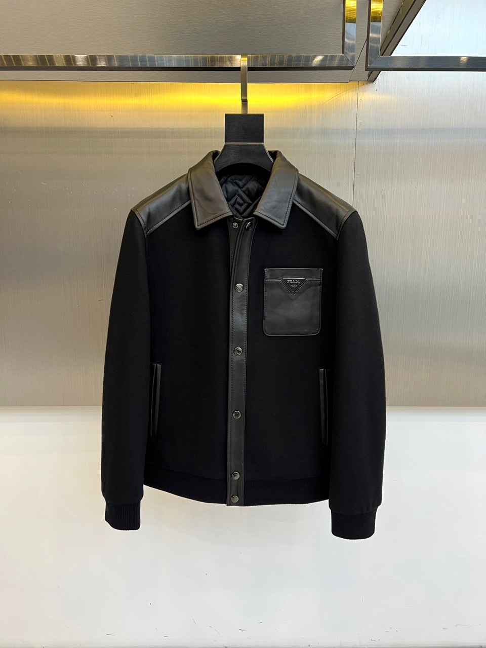 NO:712022,Prada, the new product for autumn and winter 2025, redefines urban cotton jackets with exquisite craftsmanship. This style adopts a bold material splicing design, embellished with fine-textured sheepskin on the collar, shoulder line, placket and left chest pocket, and the soft thin cotton surface used in the main body  The fabrics form a clever contrast, creating a rich visual layer and tactile experience. The classic lapel design is neat and decent, and the leather pocket on the left chest is decorated with the brand logo, which low-key highlights the identity. The cuffs are knitted with cuffs that fit the wrist, taking into account windproof practicality and complete details.  Its fabric combines 20% wool, 10% cotton and technical fibers to ensure a crisp shape and comfortable warmth. The overall silhouette is smooth and slim, and the style walks between exquisite business and contemporary leisure. Whether it is paired with formal pants or simple denim, it can be easily controlled in a variety of occasions and has become an iconic item that shapes the modern style of autumn and winter. Please follow the label instructions for professional dry cleaning care. L-4XL (model 173, 143 catties upper body size L), prada, prada, jackets &  coats, sheepskin,19860909Prad普拉达、2025秋冬新品,以精湛工艺重新定义都市棉服夹克.本款采用大胆的材质拼接设计,于领部、肩线、门襟及左胸口袋处点缀质感细腻的绵羊皮,与主体采用的柔软薄棉面料形成巧妙对比,营造丰富的视觉层次与触感体验.经典的翻领设计利落得体,左胸处的真皮口袋饰有品牌标识,低调彰显身份.袖口采用贴合手腕的针织收口,兼顾防风实用性与细节完成度. 其面料融合20羊毛、10棉及科技纤维,确保挺括造型与舒适保暖性.整体廓形流畅修身,风格游走于精致商务与当代休闲之间.无论是搭配正装裤履还是简约丹宁,皆能轻松驾驭多种场合,成为塑造秋冬摩登型格的标志性单品.请根据标签指引进行专业干洗护理.L-4XL（模特173,143斤上身L码）,,prada,prada,jackets & coats,sheepskin,,Men's clothing