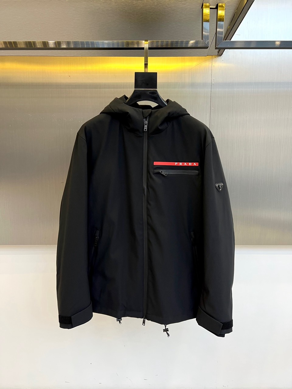 NO:712036,Prad普拉（鹅绒）、2025秋冬新品鹅绒羽绒服,以经典黑色为主调,尽显低调奢华气质.连帽设计兼顾休闲感与实用性,轻松应对多变天气.采用拉链开合设计,方便日常穿脱；左 侧胸前配备拉链口袋,巧妙融合装饰性与功能性.标志性红白配色'PRADA'标识点缀于胸前,形成鲜明视觉亮点,极具品牌辨识度.袖口处的三角形金属标志精致典雅,无声诉说着品牌 基因.整体剪裁利落流畅,既保证羽绒服的保暖性能,又不失时尚轮廓.内填充优质鹅绒,带来轻盈温暖的穿着体验.其风格完美平衡了高端时装感与日常实穿性,无论是搭配都市通勤正装 ,还是休闲出行装扮,都能为整体造型注入高级质感,成为寒冷季节中兼具温度与风度的必备单品.48-56（模特173,143斤上身50码）,,prada,prada,down  jacket,hats,19860909Prad普拉（鹅绒）、2025秋冬新品鹅绒羽绒服,以经典黑色为主调,尽显低调奢华气质.连帽设计兼顾休闲感与实用性,轻松应对多变天气.采用拉链开合设计,方便日常穿脱；左侧胸前配备拉链口袋,巧妙融合装饰性与功能性.标志性红白配色'PRADA'标识点缀于胸前,形成鲜明视觉亮点,极具品牌辨识度.袖口处的三角形金属标志精致典雅,无声诉说着品牌基因.整体剪裁利落流畅,既保证羽绒服的保暖性能,又不失时尚轮廓.内填充优质鹅绒,带来轻盈温暖的穿着体验.其风格完美平衡了高端时装感与日常实穿性,无论是搭配都市通勤正装,还是休闲出行装扮,都能为整体造型注入高级质感,成为寒冷季节中兼具温度与风度的必备单品.48-56（模特173,143斤上身50码）,,prada,prada,down jacket,hats,,Men's clothing