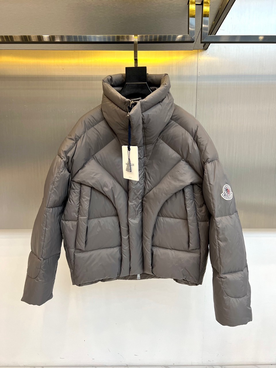 NO:712023,Meng Mouth, 2025 autumn and winter new MONCLER gray stand-up collar down jacket, presented in classic gray tones, decorated with brand logo on the shoulders, showing high-end texture in simplicity. Stand-up collar design is windproof and warm, zipper opening and closing for easy putting on and taking off, quilted lines are divided and filled  It fills the area to form a unique three-dimensional shape. The light and non-bulky wearing experience makes traveling in winter more comfortable. The short version is neat and stylish and can be paired with high-waisted trousers or skirts to elongate the body proportions. Whether it is daily commuting or weekend leisure, it can be easily controlled  A variety of occasions. Gray is versatile and classic. It can be matched with various inner wear and bottoms to create different styles of winter looks. The MONCLER brand logo is low-key and exquisite, showing extraordinary taste. This down jacket perfectly combines practicality and fashion sense. It is an indispensable and versatile item for the autumn and winter wardrobe. Warmth and style coexist, allowing you to maintain an elegant posture in the cold season. 48-56 (model 173-140 pounds upper body size 50), Moncler, skirts, down  jacket,19860909蒙口、2025秋冬新款MONCLER灰色立领羽绒服,以经典灰色调呈现,肩部饰有品牌标志,简约中彰显高级质感.立领设计防风保暖,拉链开合方便穿脱,绗缝线条分割填充区域,形成独特的立体造型,轻盈不臃肿的穿着体验让冬日出行更自在.短款版型利落有型,可搭配高腰裤装或裙装,拉长身材比例.无论是日常通勤还是周末休闲,都能轻松驾驭多种场合.灰色百搭经典,可搭配各种内搭与下装,打造不同风格的冬日造型.MONCLER品牌标志低调而精致,彰显不凡品味.这款羽绒服将实用性与时尚感完美结合,是秋冬衣橱不可或缺的百搭单品,温暖与风度并存,让你在寒冷季节依然保持优雅姿态.48-56（模特173-140斤上身50码）,,Moncler,skirts,down jacket,,Men's clothing