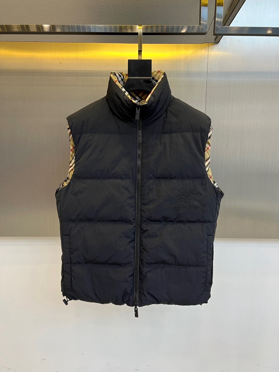 NO:712027,Burberry, 2025 autumn and winter new product reversible down vest, uses innovative double-sided design to interpret British practical aesthetics. One is made of pure black fabric with iconic plaid lining, stand-up collar design with smooth zipper closure, and exquisite embroidery details on the front; the other  One side shows the classic off-white, black and red plaid pattern, allowing for free switching between two styles through a double-sided wearable design. The fabric is made of lightweight windproof material, filled with high-quality down to ensure warmth, and practical pockets on both sides enhance functionality. Its three-dimensional tailoring takes into account both slim silhouette and flexibility.  With freedom of movement, it can be paired with a shirt to show a business casual style, or combined with a sweater to create an urban daily look. From commuting to weekend trips, this vest combines the practical innovation of double-sided wear with the brand's classic elements, becoming a fashion carrier that connects traditional heritage and modern life, interpreting Burberry's pursuit of a balance between function and aesthetics. 48-56 (model 173, 143 pounds, upper body size 50),, burberry, burberry, shirts, down  jacket,19860909Bur巴宝莉、2025秋冬新品双面穿羽绒马甲,以创新双面设计演绎英伦实用美学.一款采用纯黑色面料搭配标志性格纹内里,立领设计搭配顺滑拉链开合,正面点缀精致刺绣细节；另一面则呈现经典米白黑红格纹图案,通过双面可穿设计实现两种风格自由切换.面料选用轻量防风材质,填充优质羽绒确保保暖性,两侧实用口袋增强功能性.其立体剪裁兼顾修身廓形与活动自由度,可搭配衬衫展现商务休闲风范,亦可与针织衫组合打造都市日常造型.从通勤场合到周末出行,这款马甲以双面穿着的实用创新与品牌经典元素的融合,成为连接传统传承与现代生活的时尚载体,诠释Burberry对功能与美学的平衡追求.48-56（模特173,143斤上身50码）,,burberry,burberry,shirts,down jacket,,Men's clothing