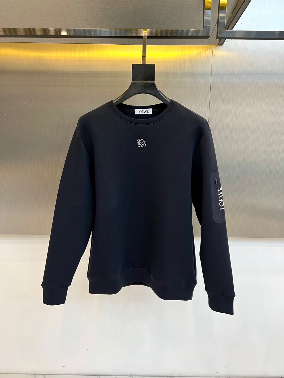 🌾罗意威、2025秋冬新款LOEWE白色圆领卫衣，以纯净白色调呈现，左胸饰有黑色品牌标志性图案，袖子上印