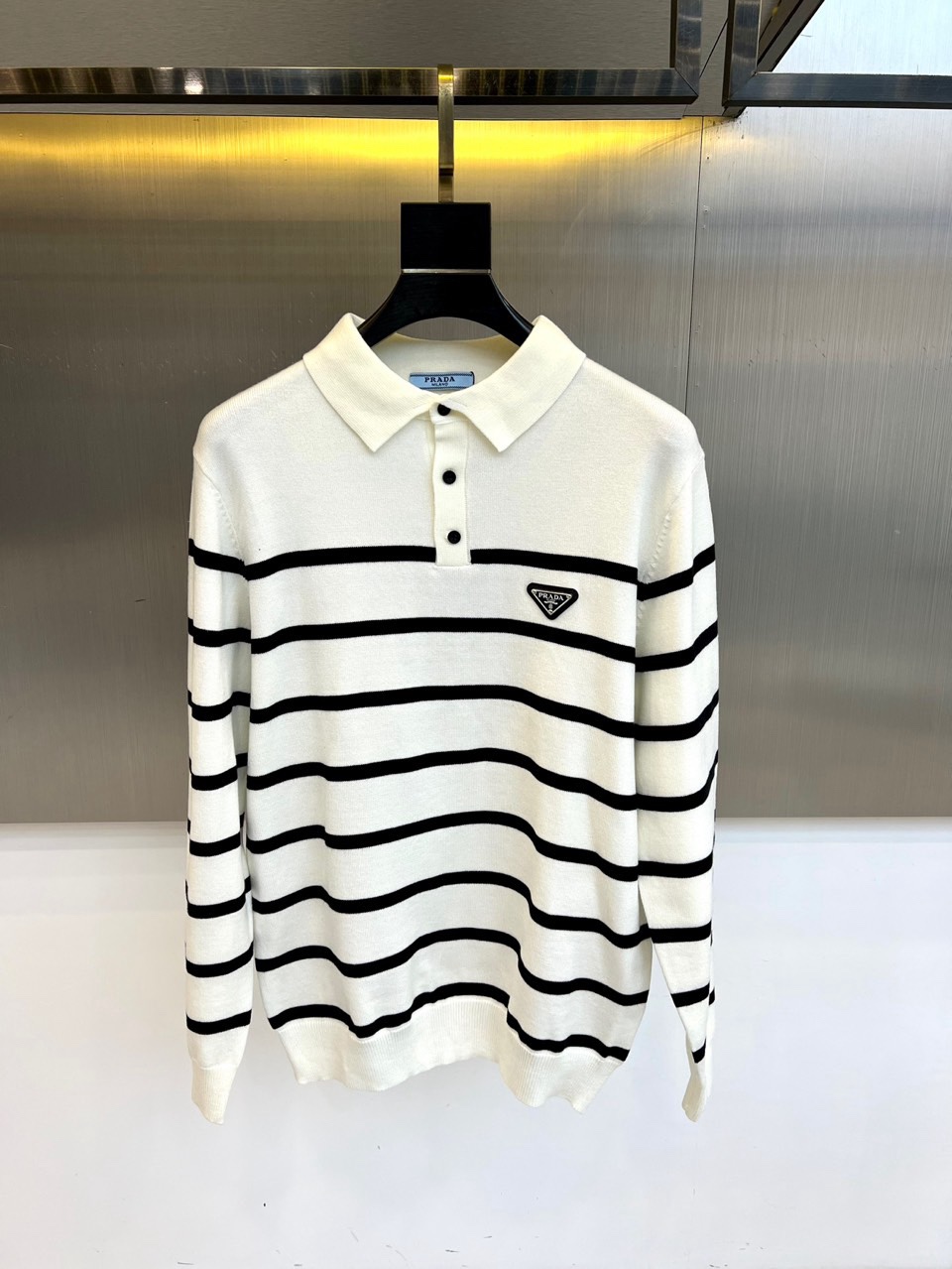 NO:726494,[After-sale after-sale] Prad, a new product for autumn and winter 2025, reshapes the contemporary wardrobe with classic long-sleeved polo sweaters. The iconic lapel design and three-button placket continue the brand's consistent simple and exquisite aesthetics. The triangular metal logo on the chest becomes the finishing touch, low-key highlighting the identity. The whole body is decorated with delicate horizontal stripe texture, visually creating a flowing rhythm and injecting rich layers into the simple silhouette.  Its style cleverly balances casualness and formality. The soft and skin-friendly blended fabric ensures all-day comfort. Whether it is paired with jeans to create a casual urban image, or combined with suit pants to present a smart casual temperament, it can easily suit a variety of occasions and become a must-have item that is both practical and high-end in autumn and winter. M-4XL (model 173, 143 pounds upper body L),, prada, prada, jeans, business suit,19860909【可年后售后】 Prad普拉、2025秋冬新品,以经典长袖polo针织衫重塑当代衣橱.标志性翻领设计与三粒扣门襟,延续品牌一贯的简约精致美学.胸前三角形金属徽标成为点睛之笔,低调彰显身份.衣身通体饰以细腻的横向条纹纹理,在视觉上构筑流动的韵律感,为简约廓形注入丰富层次. 其风格巧妙平衡休闲感与正式度.柔软亲肤的混纺面料确保全天候舒适体验.无论是搭配牛仔裤打造随性都市形象,还是与西装裤组合呈现smart casual的干练气质,都能轻松胜任多种场合,成为秋冬季节兼具实用性与高级感的必备单品.M-4XL（模特173,143斤上身L）,,prada,prada,jeans,business suit,,Men's clothing