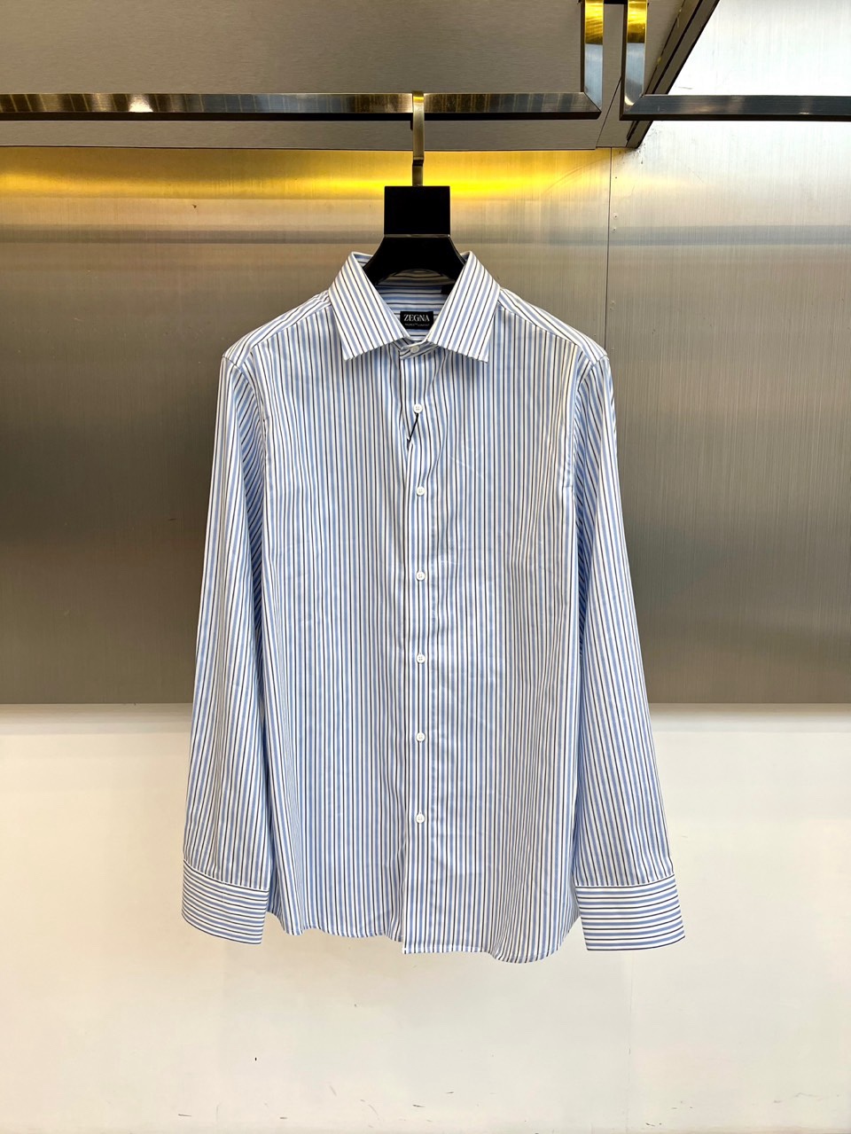 NO:730105,[After-sales service is available after the new year]  Zegna, the new men's shirt for autumn and winter 2025, uses blue and white pinstripes to interpret modern business style. This shirt has a classic lapel design, a neat and straight collar line, a same-color resin button on the front, and standard buttons on the cuffs.  Closure. The fabric uses a precise ratio of 50% Tencel and 50% cotton, which not only maintains the skin-friendly breathability of cotton, but also incorporates the smooth drape of Tencel. The body is covered with fine blue and purple vertical stripes, with clear and regular patterns, and the cuffs and body stripes perfectly echo.  Its tailoring follows the brand's iconic Italian slim fit, with a precise ergonomic shoulder line and a precisely calculated hem arc. The label clearly states that it is made in Turkey and the proportion of ingredients, demonstrating the brand's unified control of global production standards. Whether paired with a suit to create a formal business look, or worn alone to show casual elegance, this shirt can naturally show a gentleman's character with its delicate fabric texture and calm stripe pattern.  From important business meetings to high-end social occasions, this shirt has become an indispensable item in the wardrobe of elites with Zegna's consistent exquisite quality and simple design. The exquisite craftsmanship and comfortable fabrics in the details perfectly interpret the brand's balance of classics and innovation. 48-56 (model is 173,143 pounds, upper body size 50),,zegna,shirts,business suit,19860909【可年后售后】 Zegna杰尼亚、2025秋冬新品男士衬衫以蓝白细条纹演绎现代商务风尚.这款衬衫采用经典翻领设计,领口线条利落挺拔,前襟配备同色系树脂纽扣,袖口采用标准纽扣闭合.面料选用50天丝与50棉的精准配比,既保持棉质的亲肤透气性,又融入天丝的光滑垂坠感.衣身布满细密的蓝紫色竖条纹,纹路清晰规整,袖口与衣身条纹完美呼应. 其剪裁遵循品牌标志性的意式修身版型,肩线精准贴合人体工学,下摆弧度经过精密计算.标签明确标注土耳其制造与成分比例,彰显品牌对全球生产标准的统一把控.无论是搭配西装打造正式商务造型,还是单独穿着展现休闲优雅,这件衬衫都能以细腻的面料质感与沉稳的条纹图案,自然展现绅士品格. 从重要商务会议到高端社交场合,这款衬衫以杰尼亚一贯的精工品质与简约设计,成为精英人士衣橱中不可或缺的必备单品.细节处的精湛工艺与舒适面料,完美诠释品牌对经典与创新的平衡之道.48-56（模特173,143斤上身50码）,,zegna,shirts,business suit,,Men's clothing