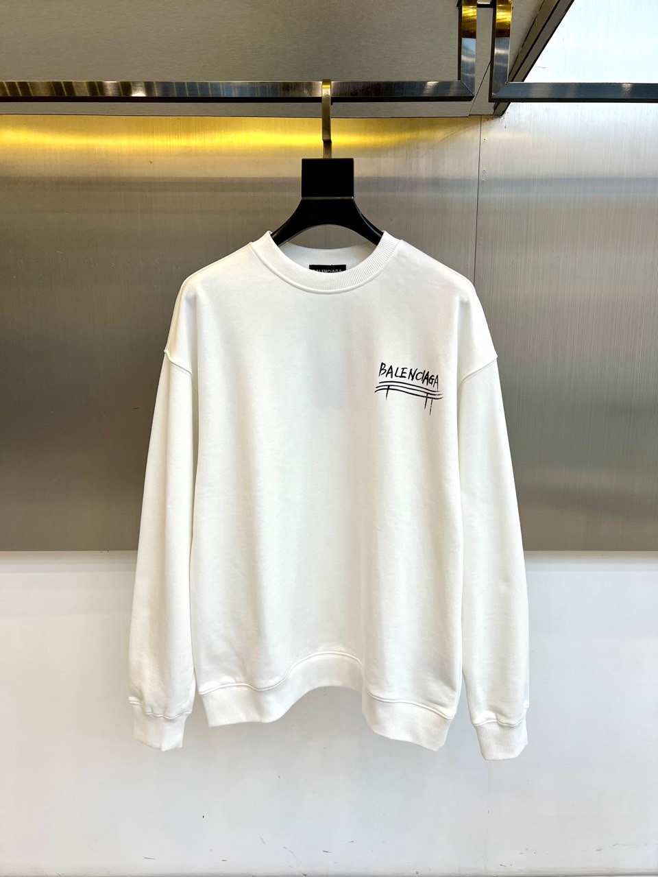 NO:730124,[After-sales service is available after the new year]  Ba Balenciaga, the new sweatshirt for autumn and winter 2025, adopts a classic round neck and long-sleeved design. The loose shoulder cut not only accommodates the body shape, but also gives the body room to stretch freely, taking into account the comfort and relaxed attitude of daily wear. In terms of style, this  This sweatshirt accurately captures the brand's iconic street sense of luxury. The words 'BALENCIAGA' on the chest are presented with artistic graffiti lines, breaking the flatness of conventional printing and bringing casual and uninhibited visual tension. It cleverly blends a simple base with individual expression.  Together. The pure white tone makes it a versatile tool. Whether it is paired with jeans to create an urban casual look, or combined with sports-style bottoms to enhance the overall trendy atmosphere, it can easily enhance the fashion level of the overall outfit and become a key item to show individual taste and cutting-edge attitude in autumn and winter. 48-56 (model is 173,143 pounds, upper body size 50),,balenciaga,balenciaga,hoodie,sweatshirts,jeans,19860909【可年后售后】 Ba巴黎世家、2025秋冬新品卫衣,款式采用经典圆领与长袖设计,宽松的落肩剪裁不仅包容身型,更赋予身体自由舒展的空间,兼顾了日常穿着的舒适感与松弛态度.风格上,这款卫衣精准捕捉了品牌标志性的街头高级感,胸前“BALENCIAGA”字样以艺术感涂鸦线条呈现,打破常规印刷的平整,带来随性不羁的视觉张力,将简约基底与个性表达巧妙融合.纯净的白色调使其成为百搭利器,无论是搭配牛仔裤塑造都市休闲造型,还是与运动风下装组合强化整体潮流氛围,都能轻松提升整体穿搭的时尚层次,成为秋冬季节展现个性品味与前沿态度的关键单品.48-56（模特173,143斤上身50码）,,balenciaga,balenciaga,hoodie,sweatshirts,jeans,,Men's clothing