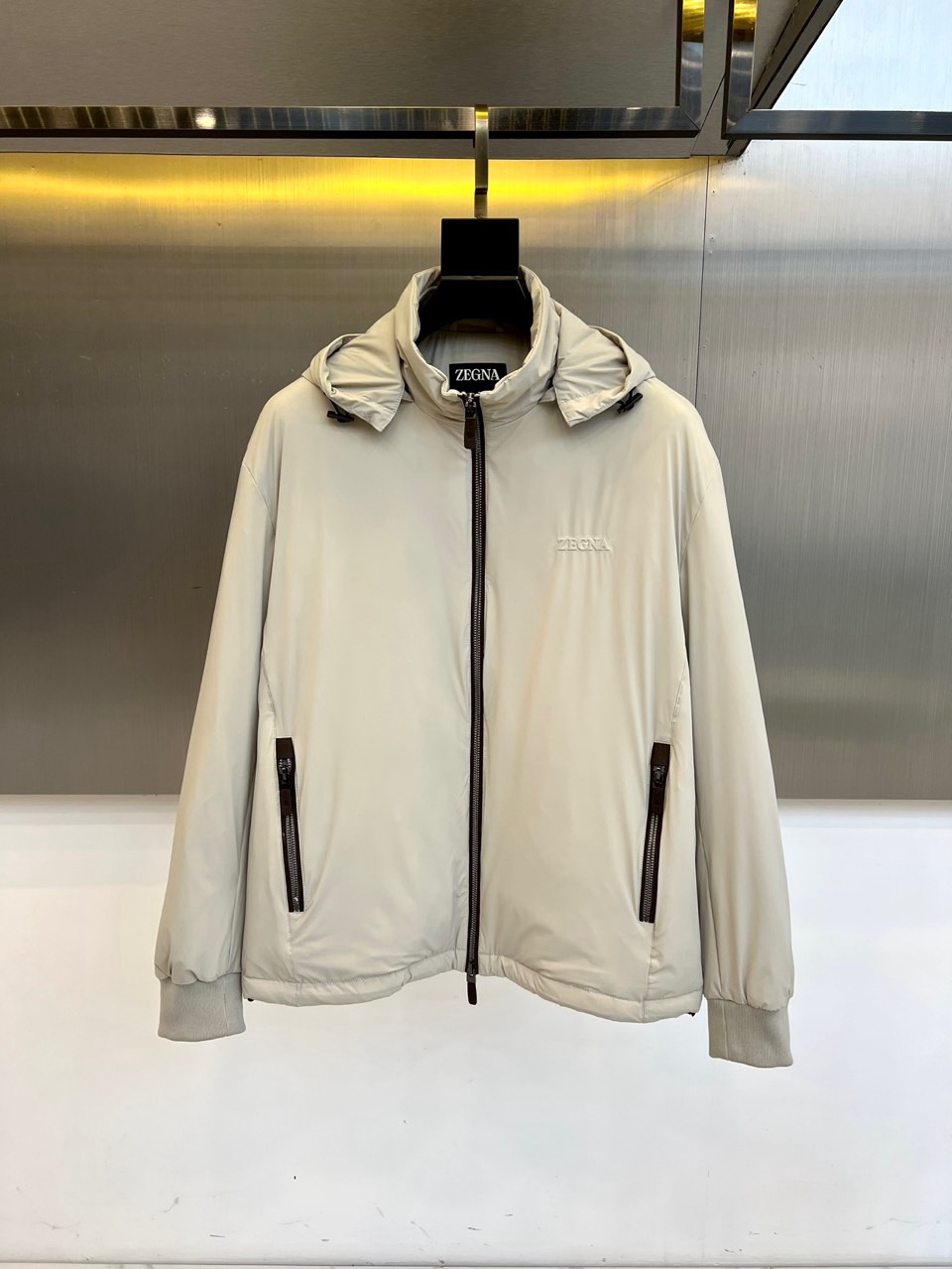 NO:730174,Zegna's new autumn and winter 2025 down jacket interprets modern urban aesthetics with light gray texture. This hooded down jacket adopts minimalist three-dimensional tailoring, and the front is equipped with a dark brown zipper opening and closing system, which forms a sharp visual contrast with the light gray fabric of the main body. Embellishment on the left chest  The brand's iconic embroidered logo is also decorated with brand letter details on the inside of the collar. The diagonal pockets on both sides are equipped with invisible zippers, and the cuffs and hem are closed with elastic ribs to enhance wind resistance. The fabric is made of polyamide and the lining is polyester fiber, ensuring light warmth and wear resistance.  It combines both sex and function. Its design perfectly combines practical functions with Italian elegance, and maintains a crisp silhouette through precise quilting technology. Whether it is a business commute or a weekend trip, this down jacket can be adapted to a variety of occasions with a low-key and luxurious texture, showing the calm demeanor of a contemporary gentleman.  The exquisite craftsmanship and exquisite material selection in the details continue Zegna's persistent pursuit of quality, becoming a must-have item in the autumn and winter wardrobe that is both practical and fashionable. 48-56 (173,143 pounds in a certain place, upper body size 50),,zegna,down  jacket,hats,19860909Zegna杰尼亚、2025秋冬新品羽绒服以浅灰质感演绎现代都市美学.这款连帽羽绒服采用极简立体剪裁,前襟配备深棕色拉链开合系统,与主体浅灰色面料形成鲜明视觉对比.左胸点缀品牌标志性刺绣标识,衣领内侧同样饰有品牌字母细节.两侧斜插口袋配备隐形拉链设计,袖口与下摆采用弹性罗纹收口增强防风性能.面料采用聚酰胺材质,衬里为聚酯纤维,确保轻盈保暖与耐磨性兼具.其设计将实用功能与意式优雅完美融合,通过精准的绗缝工艺保持廓形挺括.无论是商务通勤还是周末出行,这款羽绒服都能以低调奢华的质感适配多种场合,展现当代绅士的从容风度.细节处的精湛工艺与考究材质选择,延续杰尼亚对品质的执着追求,成为秋冬衣橱中兼具实穿性与时尚感的必备单品.48-56（某地173,143斤上身50码）,,zegna,down jacket,hats,,Men's clothing