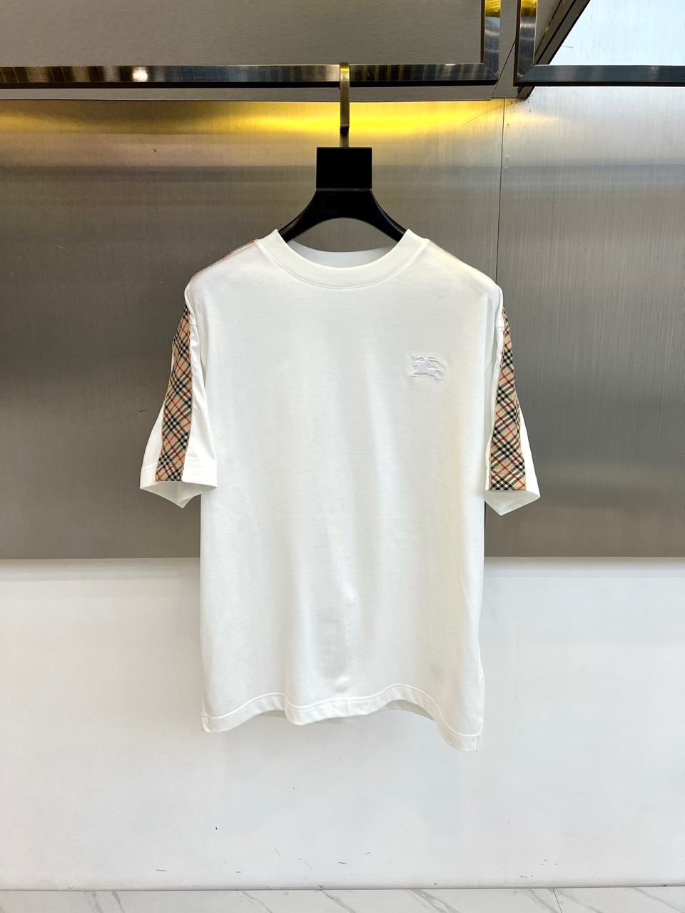 NO:732958,Burberry, the new men's T-shirt for spring and summer 2026, reinterprets the brand's iconic elements with exquisite craftsmanship. The style adopts a loose-cut round neck version. The biggest highlight is that the sleeves on both sides are cleverly spliced with the brand's classic plaid fabric, which contrasts with the exquisite three-dimensional horse embroidery badge on the left chest. Its style perfectly combines the relaxation of street fashion and the timeless style of British luxury goods, turning the brand's profound heritage into daily life.  A statement of personality that is often worn. Whether paired with casual trousers to create an urban casual style, or layered with denim items to create a fashionable look, this T-shirt can become an elegant carrier that connects the classic and the contemporary, showing the wearer's effortless fashion attitude. 48-56 (model 173,143 pounds, upper body size 50),, burberry, burberry, tees, t-shirt,19860909Bur巴宝莉、2026春夏新品男士T恤,以精湛工艺重新诠释品牌标志性元素.款式采用宽松剪裁的圆领版型,最大亮点在于两侧袖身巧妙拼接品牌经典格纹面料,与左胸处的精致立体骏马刺绣徽章相映成趣.其风格完美融合了街头潮流的松弛感与英伦奢侈品的隽永格调,将品牌深厚底蕴化为日常穿着的个性宣言.无论是搭配休闲裤装演绎都市闲适风,还是与牛仔单品层叠塑造时尚造型,这件T恤都能成为连接经典与当代的优雅载体,展现穿着者举重若轻的时尚态度.48-56（模特173,143斤上身50码）,,burberry,burberry,tees，t-shirt,,Men's clothing