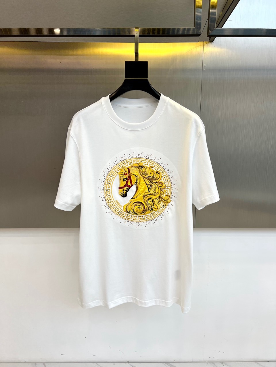 NO:732963,Vers Versace's 2026 spring and summer [Year of the Horse Limited] series of men's T-shirts features a classic round neck short-sleeved silhouette that interprets the fusion of Italian luxury and street style. The iconic design focuses on the gorgeous badge-like pattern on the chest, a delicately depicted horse head image, surrounded by complex baroque-style patterns, and the relief-like texture highlights the exquisite craftsmanship and the brand's strong visual genes. This pattern is not only an identity mark, but also an artistic self-expression.  The item is made of high-quality pure cotton fabric to ensure a skin-friendly and breathable wearing feel. It is also specially integrated with herbal antibacterial and anti-disease finishing technology to inject reassuring protection into daily wear. The essence of its design is to perfectly balance the gorgeous elements of classicism with the modern minimalist silhouette, whether it is paired with casual trousers, it will show off your style.  With a relaxed attitude, or layered with fashionable jackets to enhance the overall look, it can easily become the focus and create a highly recognizable spring and summer luxury casual style. 48-56 (model weighs 173,143 pounds, upper body size 50),,versace,versace,jackets  & coats,T-shirt,tees,t-shirt,19860909Vers范思哲、2026春夏【马年限定】系列男士T恤,以经典圆领短袖廓形,诠释意式奢华与街头型格的融合.标志性设计聚焦于胸前的华丽徽章式图案,精致描绘的马首形象,周身环绕繁复的巴洛克风格纹饰,浮雕般的质感凸显精湛工艺与品牌强大的视觉基因.此图案不仅是身份标识,更是艺术化的自我表达. 单品选用高品质纯棉面料,确保亲肤透气的穿着体感.更特别融入本草抗菌抗病整理技术,为日常穿搭注入安心守护.其设计精髓在于将古典主义的华丽元素与现代极简的版型完美平衡,无论是搭配休闲裤装彰显不羁态度,或与时尚外套层叠搭配提升整体造型感,都能轻松成为焦点,打造极具辨识度的春夏奢华休闲风格.48-56（模特173,143斤上身50码）,,versace,versace,jackets & coats,T-shirt,tees，t-shirt,,Men's clothing
