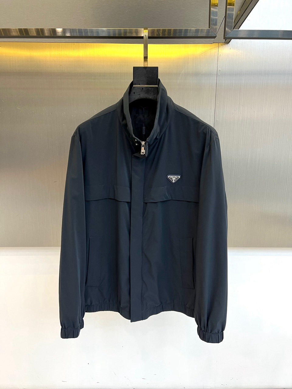 NO:732959,Prad, the new men's jacket for spring and summer 2026, uses a simple stand-up collar design to outline a neat silhouette. The iconic metal triangle logo is embellished on the chest, highlighting the brand identity in minimalism. The pockets on both sides are cleverly integrated into smooth lines, combining practicality and structural beauty. The tailoring is precise and the lines are clean and neat.  This product uses the brand's exclusive high-performance fabric, with a crisp and drapey texture to ensure a stylish silhouette, comfort and breathability when worn. Its design perfectly balances modernist aesthetics and practical functions, with a style that walks the line between urban leisure and business occasions.  Whether paired with trousers from the same series to create a complete look, or mixed and matched with daily items, it can calmly show a restrained and high-end fashion attitude, becoming a key item in the spring and summer wardrobe to enhance the overall texture. 48-56 (model is 173, 143 pounds, upper body size 50),, prada, prada, jackets & coats,19860909Prad普拉、2026春夏新品男士夹克,以简约立领设计勾勒利落廓形.胸前点缀标志性的金属三角徽标,于极简中彰显品牌身份.两侧口袋巧妙融入流畅线条,兼具实用性与结构美感.剪裁精准,线条干净利落. 本品选用品牌专属的高性能面料,质地挺括且富有垂坠感,确保穿着时轮廓有型、舒爽透气.其设计完美平衡了现代主义美学与实用功能,风格上游走于都市休闲与商务场合之间. 无论是搭配同系列裤装打造完整造型,或与日常单品混搭,皆能从容展现克制而高级的时尚态度,成为春夏衣橱中提升整体质感的关键单品.48-56（模特173,143斤上身50码）,,prada,prada,jackets & coats,,Men's clothing