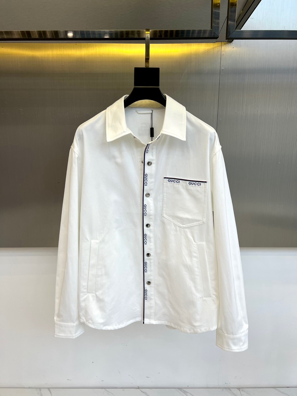 NO:732964,Gucci, the 2026 spring and summer men's jacket, interprets contemporary casual style with neat lapels and classic jacket silhouette. The placket is closed with unique multiple buttons, and the buttons and the edge of the left breast pocket are decorated with repeated 'GUCCI' brand logo webbing. This iconic detail not only enhances recognition, but also builds a rich visual layer and exquisite texture. The overall fit is loose and comfortable, providing comfortable space for daily wear.  The item is made of cotton. The fabric is crisp, breathable and skin-friendly, and complies with the standards of wearing without direct contact with the skin. Its design cleverly combines the practical spirit of the classic work jacket with the brand's unique luxury aesthetics, whether worn with a simple T-shirt or shirt to create a layered look, or worn alone with casual wear.  Casual trousers can easily create a variety of styles from urban travel to suburban walks, becoming a must-have item in the spring and summer wardrobe that combines texture and style. 48-56 (model weighs 173,143 pounds, upper body size 50),, gucci, gucci, jackets  & coats,shirts,tees,t-shirt,19860909Gucc古驰、2026春夏男士外套,以利落翻领与经典茄克廓形,诠释当代休闲风尚.门襟采用别致的多粒纽扣闭合,纽扣旁与左胸口袋边缘均饰以重复排列的“GUCCI”品牌标识织带,这一标志性细节在提升辨识度的同时,构筑出丰富的视觉层次与精致质感.整体版型宽松自如,为日常穿着提供舒适空间. 单品采用棉制成,面料挺括且透气亲肤,符合非直接接触皮肤的穿着标准.其设计巧妙融合了经典工装茄克的实用精神与品牌独有的奢华美学,无论是内搭简约T恤、衬衫打造层次感造型,或单独搭配休闲裤装,都能轻松塑造从都市出行到近郊漫步的多样风格,成为春夏衣橱中兼具质感与型格的必备单品.48-56（模特173,143斤上身50码）,,gucci,gucci,jackets & coats,shirts,tees，t-shirt,,Men's clothing