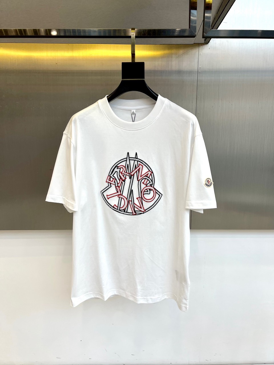 NO:734832,Mon, a new T-shirt for spring and summer 2026, uses a classic round neck short-sleeved silhouette to demonstrate exquisite craftsmanship in simplicity. Its core design lies in the iconic three-dimensional embroidery pattern on the chest, with neat lines outlining a unique combination of letters, highlighting strong brand recognition and modern beauty. The exquisite logo patch on the left cuff highlights the pursuit of quality in every detail. The single product is made of pure cotton fabric, presenting a soft and skin-friendly wearing experience, ensuring all-day comfort.  The overall design abandons complexity and condenses the brand's genes into simple outlines and exquisite details, which are perfectly suitable for a variety of leisure scenes. Whether it is daily travel or urban strolling, it can easily create a low-key and stylish spring and summer look, becoming an ideal item that connects practicality and fashion attitude. 48-56 (model weighs 173,143 pounds, upper body size 50), Moncler, T-shirt, tees, t-shirt,19860909Mon蒙口、2026春夏新品T恤,以经典圆领短袖廓形,演绎简约中的精湛工艺.其核心设计在于胸前标志性的立体刺绣图案,利落线条勾勒出独特的字母组合,彰显强烈的品牌辨识度与现代美感.左袖口处的精致标识贴片,于细微处凸显品质追求.单品精选纯棉面料,呈现柔软亲肤的穿着体感,确保了全天候的舒适自在.整体设计摒弃繁复,将品牌基因浓缩于简洁的轮廓与精致的细节之中,完美适配多种休闲场景,无论是日常出行还是都市漫步,都能轻松塑造低调而富有格调的春夏造型,成为连接实用性与时尚态度的理想单品.48-56（模特173,143斤上身50码）,,Moncler,T-shirt,tees，t-shirt,,Men's clothing