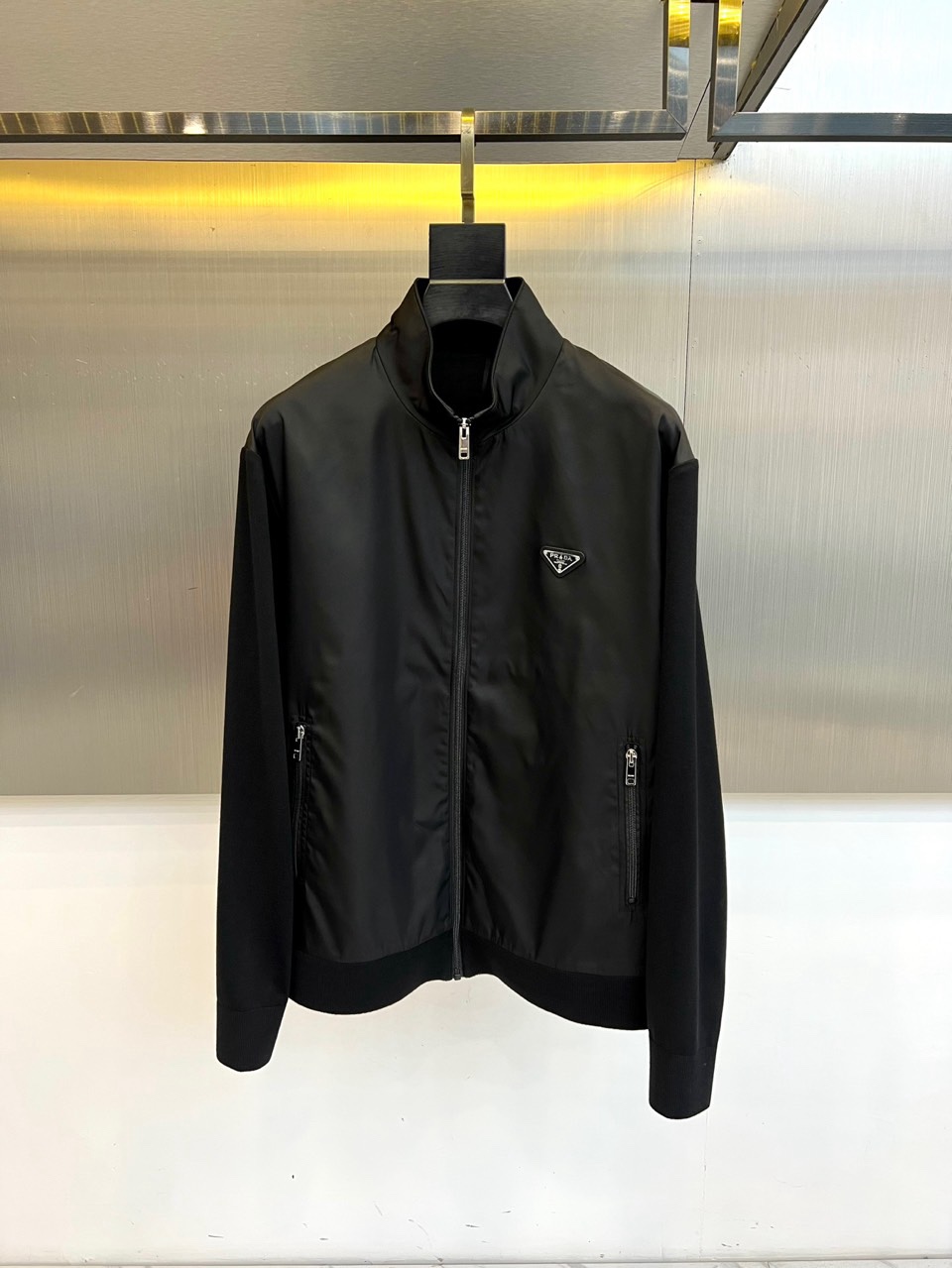 NO:734853,Prad, the new spring and summer 2026 jacket, outlines a modern urban silhouette with a neat stand-up collar and smooth metal zipper opening and closing. The brand logo is embellished on the left chest to enhance the texture of the details. The highlight of its design is the innovative use of different materials for splicing the shoulders and sleeves, cleverly creating a rich layering and structural beauty. The zipper pockets on both sides combine practical functions with smooth styling.  The main body of this product is made of high-performance fabrics made of nylon to ensure stiffness, wear resistance and excellent wind resistance; the splicing part is a blend of 81.3 viscose fiber and 18.7 polyester fiber, providing soft elasticity and comfortable touch; the lining is nylon, ensuring smooth putting on and taking off. The overall tailoring is precise, perfectly balancing looseness and three-dimensionality.  In terms of style, it cleverly combines the functional sense of sportswear with the simple lines of high-end fashion. Whether it is used for daily commuting to create a capable image, or to show individual attitude in casual gatherings, it can be easily controlled and has become a key item to enhance the overall style and style. 48-56 (model is 173,143 pounds, upper body size 50),, prada, prada, jackets & coats,19860909Prad普拉、2026春夏新品夹克,以利落立领与顺滑金属拉链开合,勾勒现代都市廓形.左胸点缀品牌标识,强化细节质感.其设计亮点在于肩部与袖身创新运用不同材质进行拼接,巧妙构建出丰富的层次与结构美感.两侧拉链口袋兼顾实用机能与造型流畅度. 本品精选高性能面料主体前片采用锦纶,确保挺括耐磨与出色防风性；拼接部分则融合81.3粘纤与18.7聚酯纤维,提供柔软的弹力与舒适触感；里料为锦纶,保障穿脱顺滑.整体剪裁精准,完美平衡了宽松度与立体感. 风格上,它巧妙融合了运动装的机能感与高端时装的简约线条,无论是用于日常通勤塑造干练形象,或是在休闲聚会中展现个性态度,皆能轻松驾驭,成为提升整体造型层次与型格的关键单品.48-56（模特173,143斤上身50码）,,prada,prada,jackets & coats,,Men's clothing