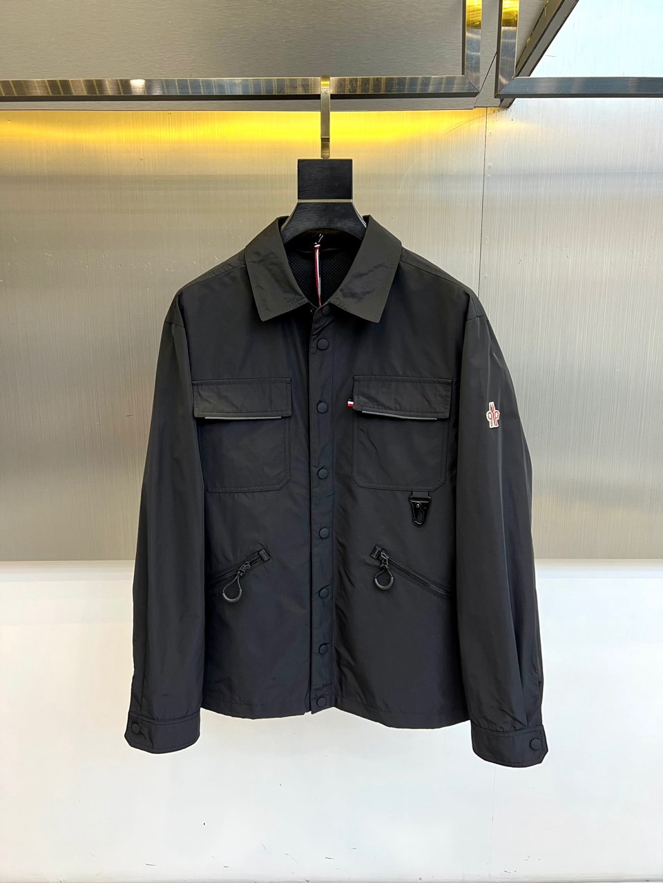 NO:734857,Mon's new spring/summer 2026 jacket interprets modern urban functional style with its neat lapel and button closure design. Its design highlight lies in its well-layered multi-pocket structure, with two three-dimensional large pockets on the chest setting a practical tone. Three-dimensional pockets decorated with zippers and buckles are embellished on both sides of the hem, cleverly blending functional details and fashion ingenuity. The upper arm of the left sleeve is decorated with a brand logo, low-key highlighting its identity.  The tailoring lines are smooth, the silhouette is crisp, and the shoulders and armholes are neatly structured. This product uses polyester fiber fabric to ensure that the clothing has excellent stiffness, wear resistance and easy care, and can adapt to the changing climate of spring and summer and the needs of frequent daily wear.  The overall style accurately grasps the balance between pragmatism and urban fashion, transforming workwear inspiration into exquisite daily wear. Whether it is paired with a simple interior to create a capable commuting image, or integrated into a casual look to show a personal attitude, it can become a key item to enhance the overall style level and functionality. 48-56 (model 173, 143 pounds, upper body size 50), Moncler, jackets & coats,19860909Mon蒙口、2026春夏新品夹克,以利落翻领与纽扣开合设计,诠释现代都市机能风格.其设计亮点在于层次分明的多口袋结构,胸前两个立体大口袋奠定实用基调,下摆两侧则点缀带拉链与环扣装饰的立体口袋,巧妙融合功能细节与时尚巧思.左袖上臂饰有品牌标识,低调彰显身份. 剪裁线条流畅,版型挺括,肩部与袖笼结构利落.本品选用聚酯纤维面料,确保衣物具备出色的挺括感、耐磨性与易打理性,适应春夏多变气候与日常频繁穿着的需求. 整体风格精准把握了实用主义与都市时尚的平衡,将工装灵感转化为精致日常着装.无论是搭配简约内塑造干练通勤形象,或是融入休闲造型展现个性态度,皆能成为提升整体造型层次与功能性的关键单品.48-56（模特173,143斤上身50码）,,Moncler,jackets & coats,,Men's clothing