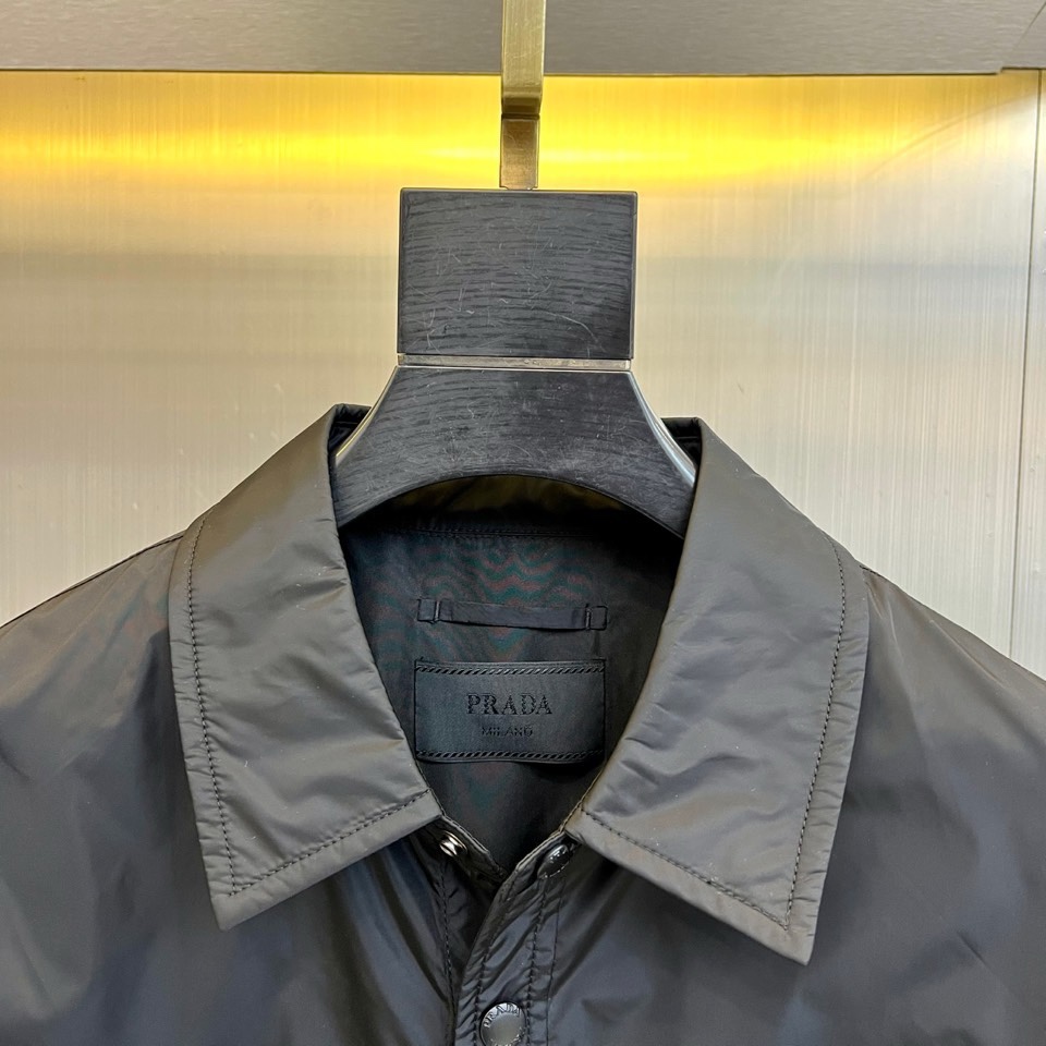 Prad普拉达、2026春夏男士夹克，以简约线条重塑都市机能美学。款式采用衬衫式翻领与利落宽松剪裁，门襟