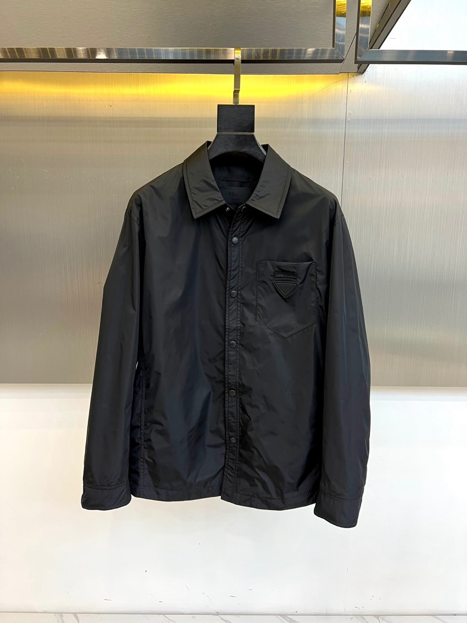 Prad普拉达、2026春夏男士夹克，以简约线条重塑都市机能美学。款式采用衬衫式翻领与利落宽松剪裁，门襟