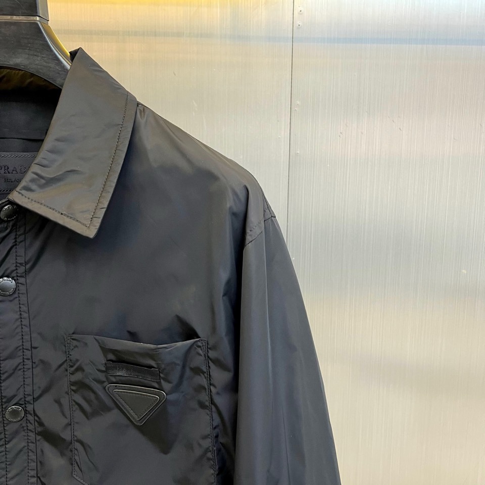 Prad普拉达、2026春夏男士夹克，以简约线条重塑都市机能美学。款式采用衬衫式翻领与利落宽松剪裁，门襟