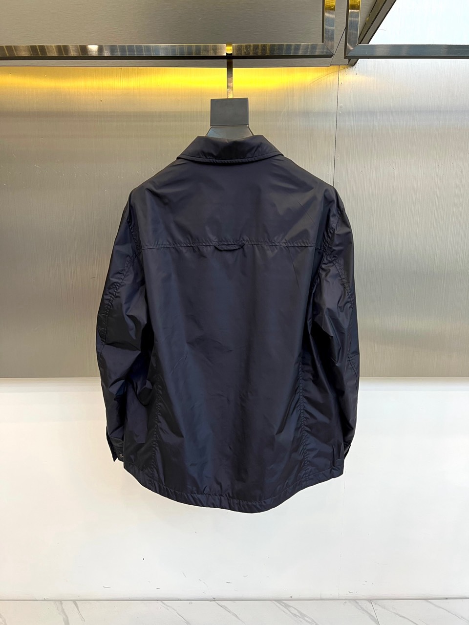 Prad普拉达、2026春夏男士夹克，以简约线条重塑都市机能美学。款式采用衬衫式翻领与利落宽松剪裁，门襟