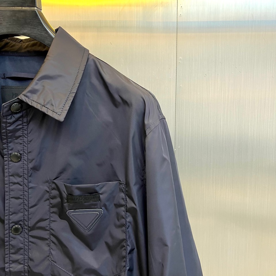 Prad普拉达、2026春夏男士夹克，以简约线条重塑都市机能美学。款式采用衬衫式翻领与利落宽松剪裁，门襟