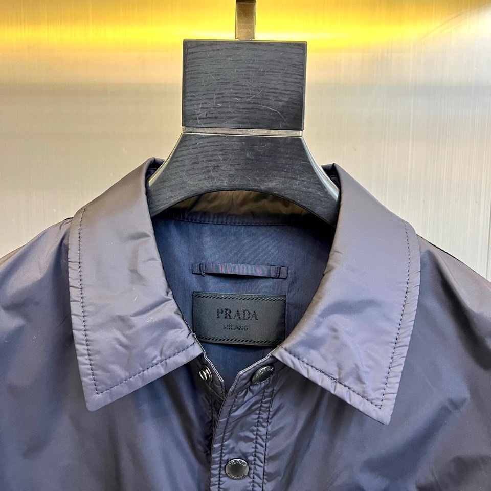 Prad普拉达、2026春夏男士夹克，以简约线条重塑都市机能美学。款式采用衬衫式翻领与利落宽松剪裁，门襟