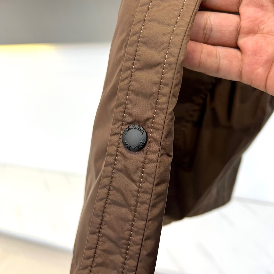 Prad普拉达、2026春夏男士夹克，以简约线条重塑都市机能美学。款式采用衬衫式翻领与利落宽松剪裁，门襟