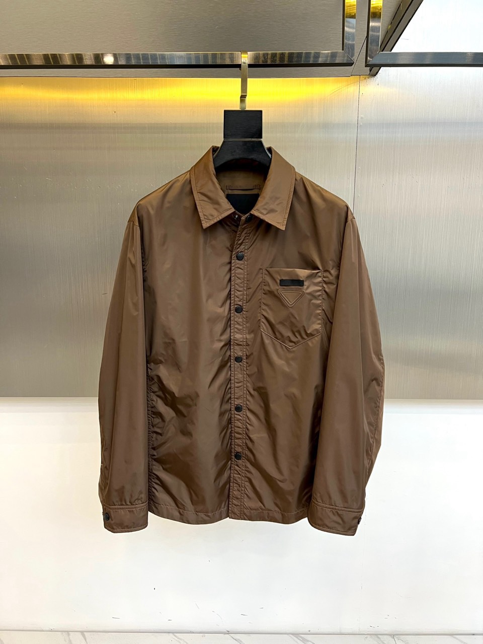 Prad普拉达、2026春夏男士夹克，以简约线条重塑都市机能美学。款式采用衬衫式翻领与利落宽松剪裁，门襟