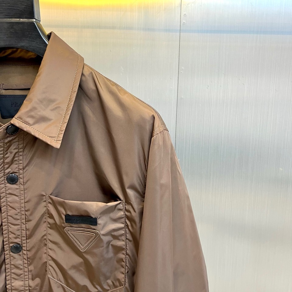 Prad普拉达、2026春夏男士夹克，以简约线条重塑都市机能美学。款式采用衬衫式翻领与利落宽松剪裁，门襟