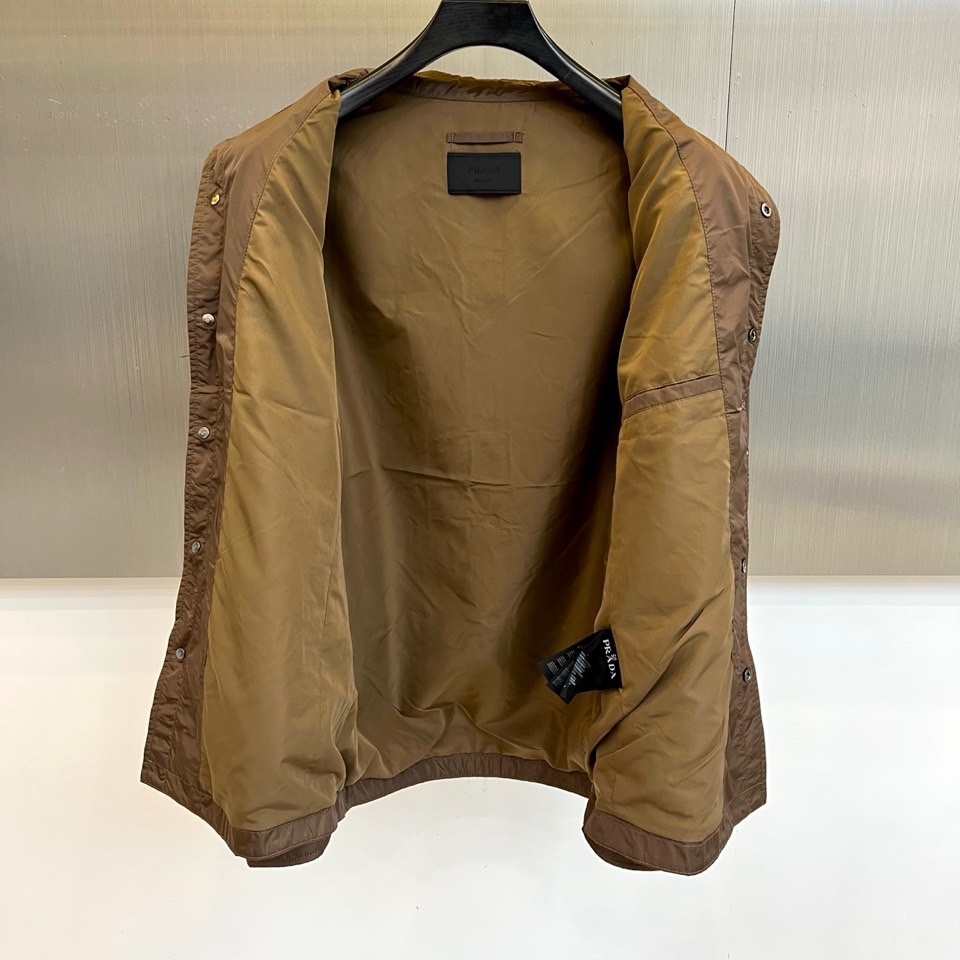 Prad普拉达、2026春夏男士夹克，以简约线条重塑都市机能美学。款式采用衬衫式翻领与利落宽松剪裁，门襟