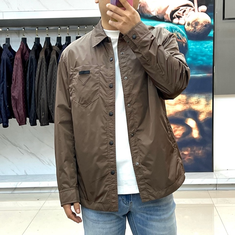 Prad普拉达、2026春夏男士夹克，以简约线条重塑都市机能美学。款式采用衬衫式翻领与利落宽松剪裁，门襟